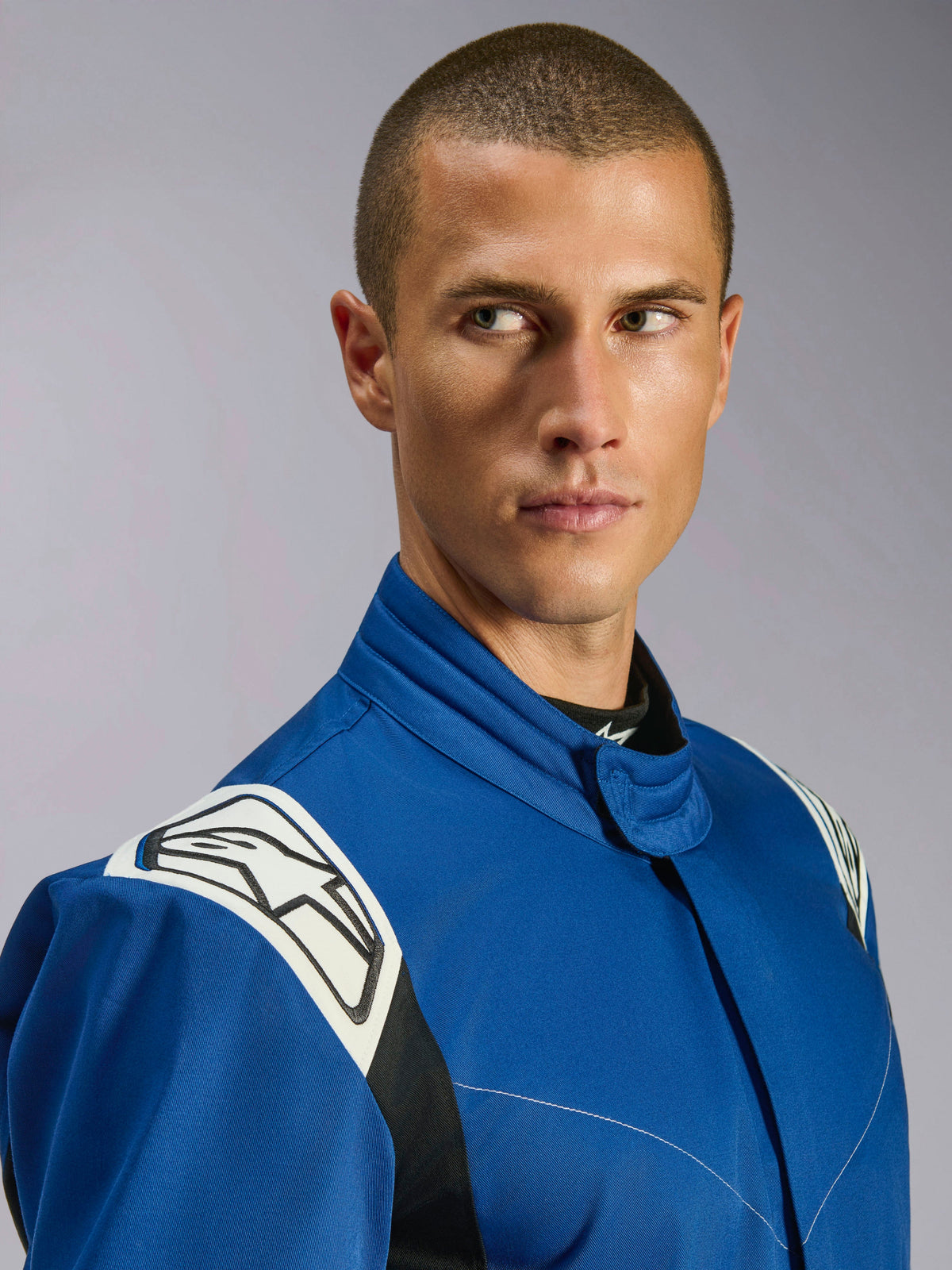 Alpinestars Kart Indoor V2 Suit, Blue Karting Suit, close-up view of male model, white shoulder panels with black star logo, ergonomic collar, durable single-layer twill for recreational racing.