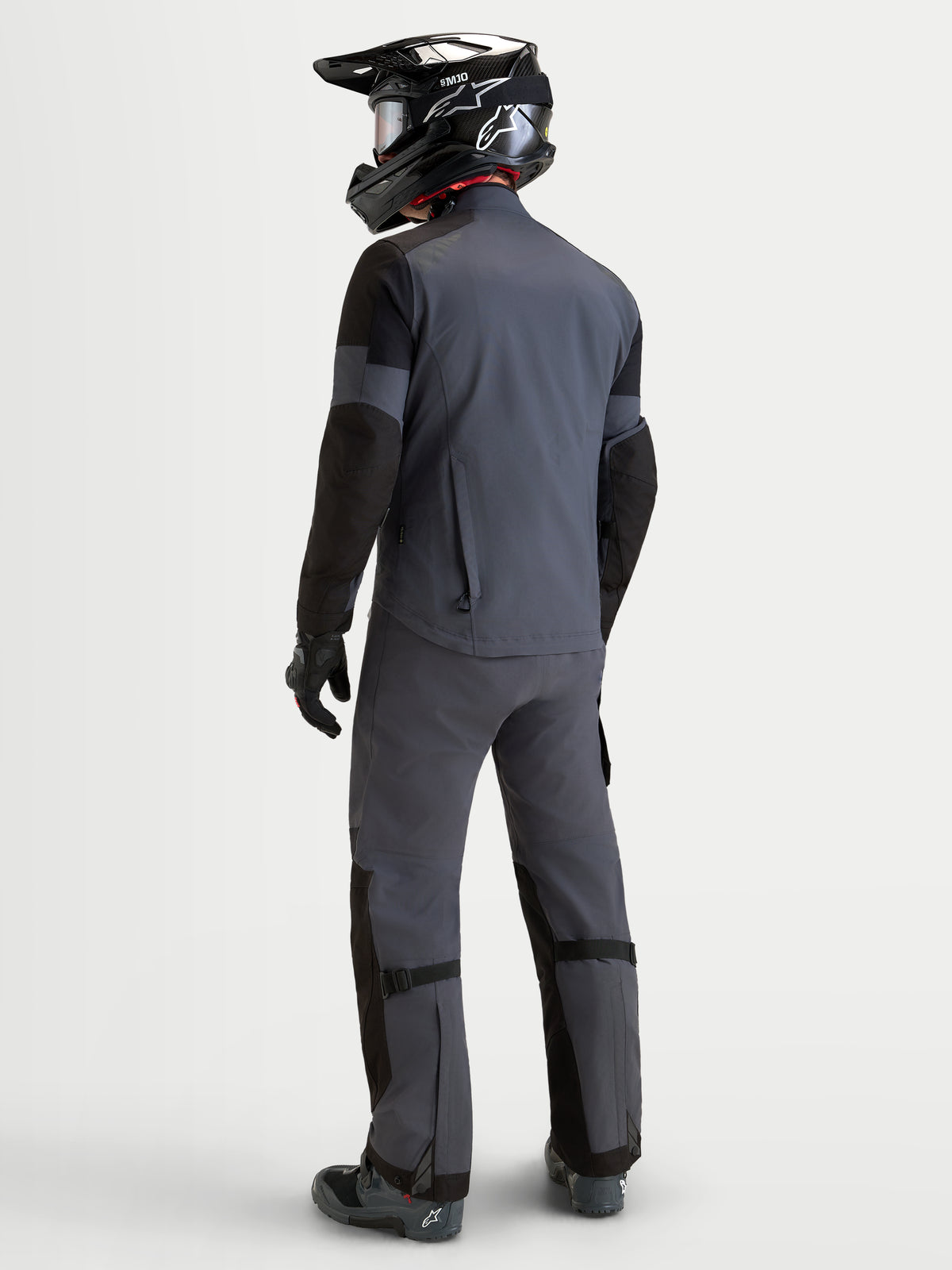 Alpinestars Arenis Gore-Tex Gear Set, men's adventure touring motorcycle jacket and pants in gray and black, rear view on a model wearing matching gear and helmet, waterproof all-terrain riding apparel
