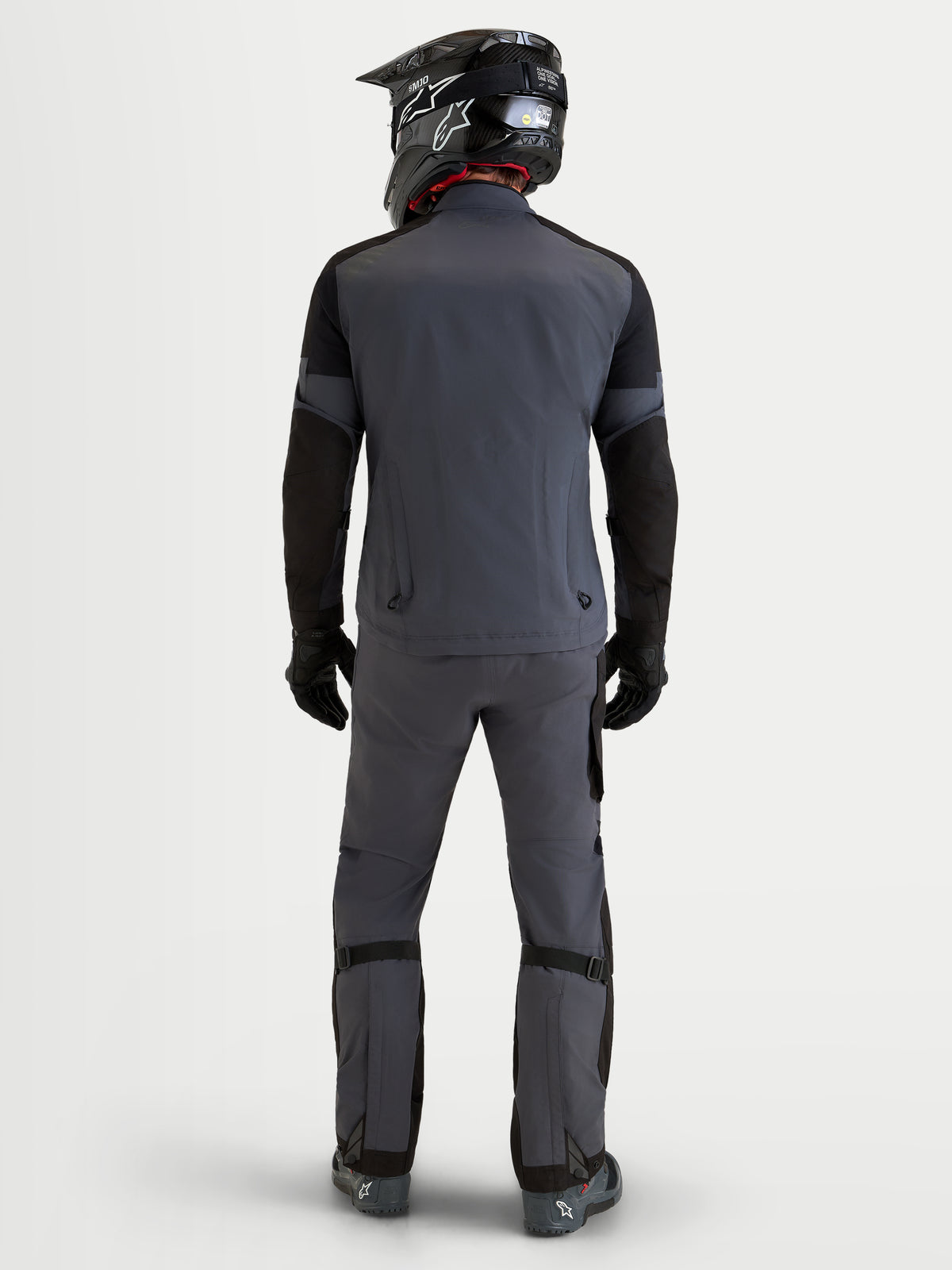 Alpinestars Arenis Gore-Tex Gear Set, men's adventure touring motorcycle jacket and pants in dark gray and black, rear profile view on a model wearing a matching helmet and riding gear, waterproof GORE-TEX all-terrain apparel.