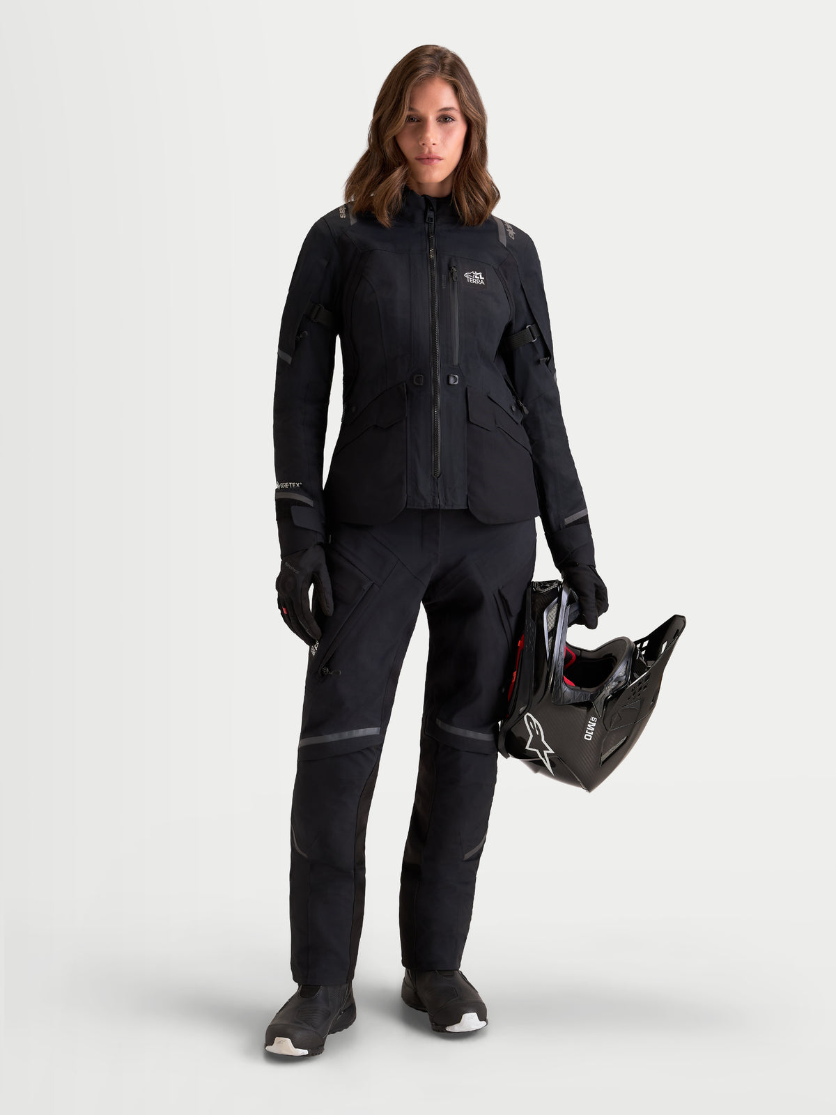 Alpinestars Stella St-7 V2 2L Gore-Tex Pants, women's adventure touring motorcycle pants in black, front view worn by a model holding a helmet and matching jacket