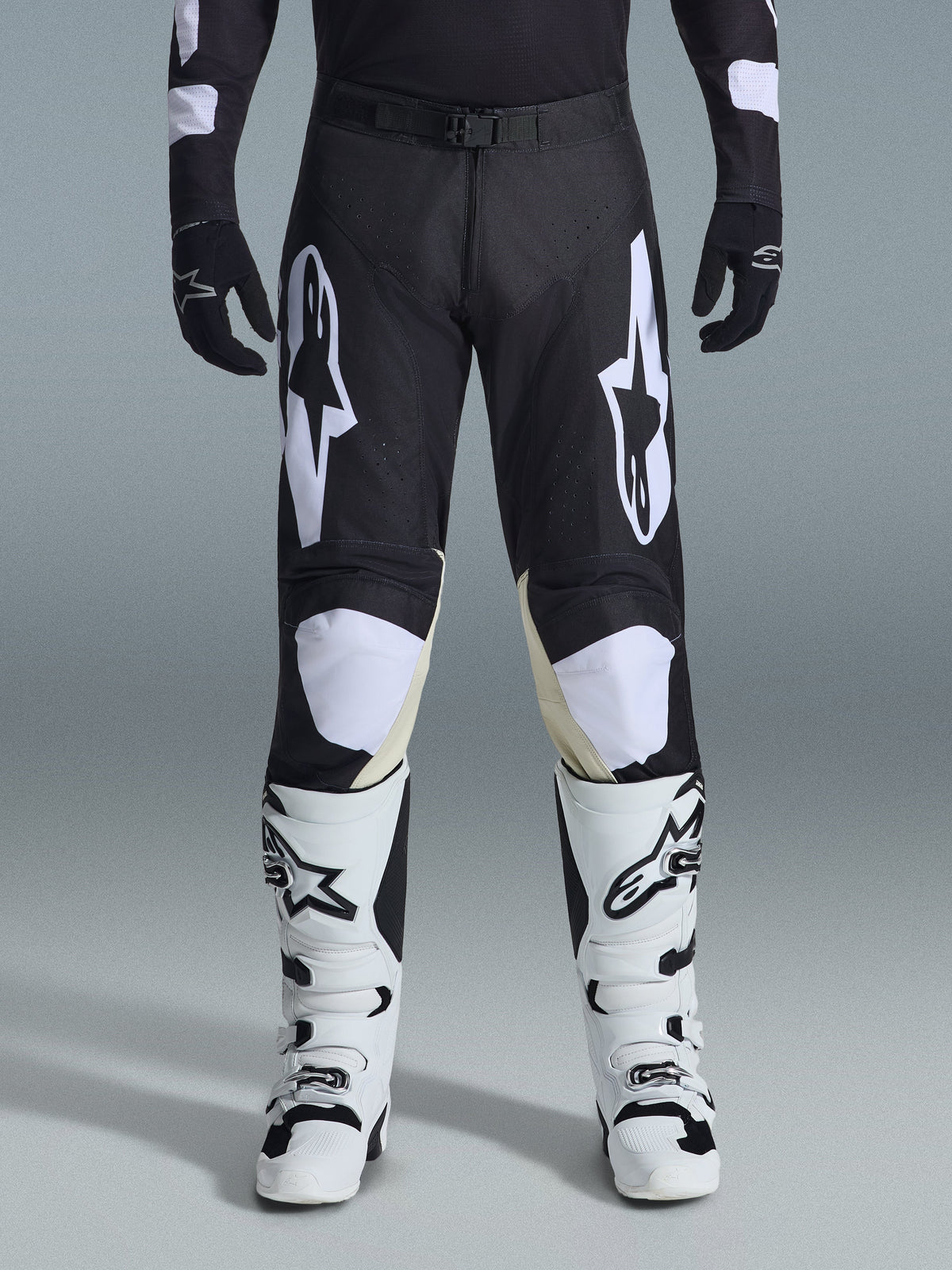 Alpinestars 2026 Racer Air Riway Pants, Motocross Pants, Black and White, featuring bold white Alpinestars logos on the thighs and knee panels, paired with white and black motocross boots and black gloves, athletic race-fit design for off-road riding
