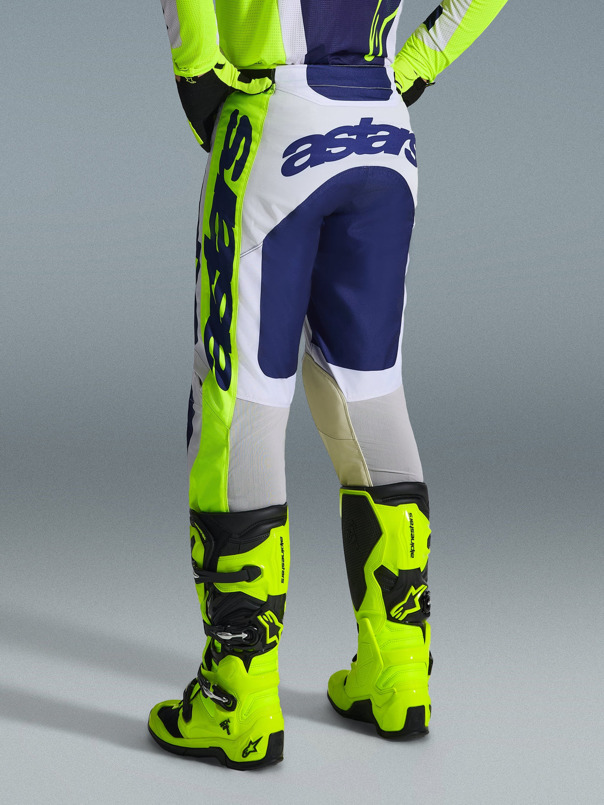 Alpinestars 2026 Racer Air Riway Pants, Motocross Pants, Light Gray, Yellow Fluo, and Blue, rear view showing 'astars' logo on the seat and side, worn with matching fluo yellow motocross boots, athletic race fit designed for off-road performance.