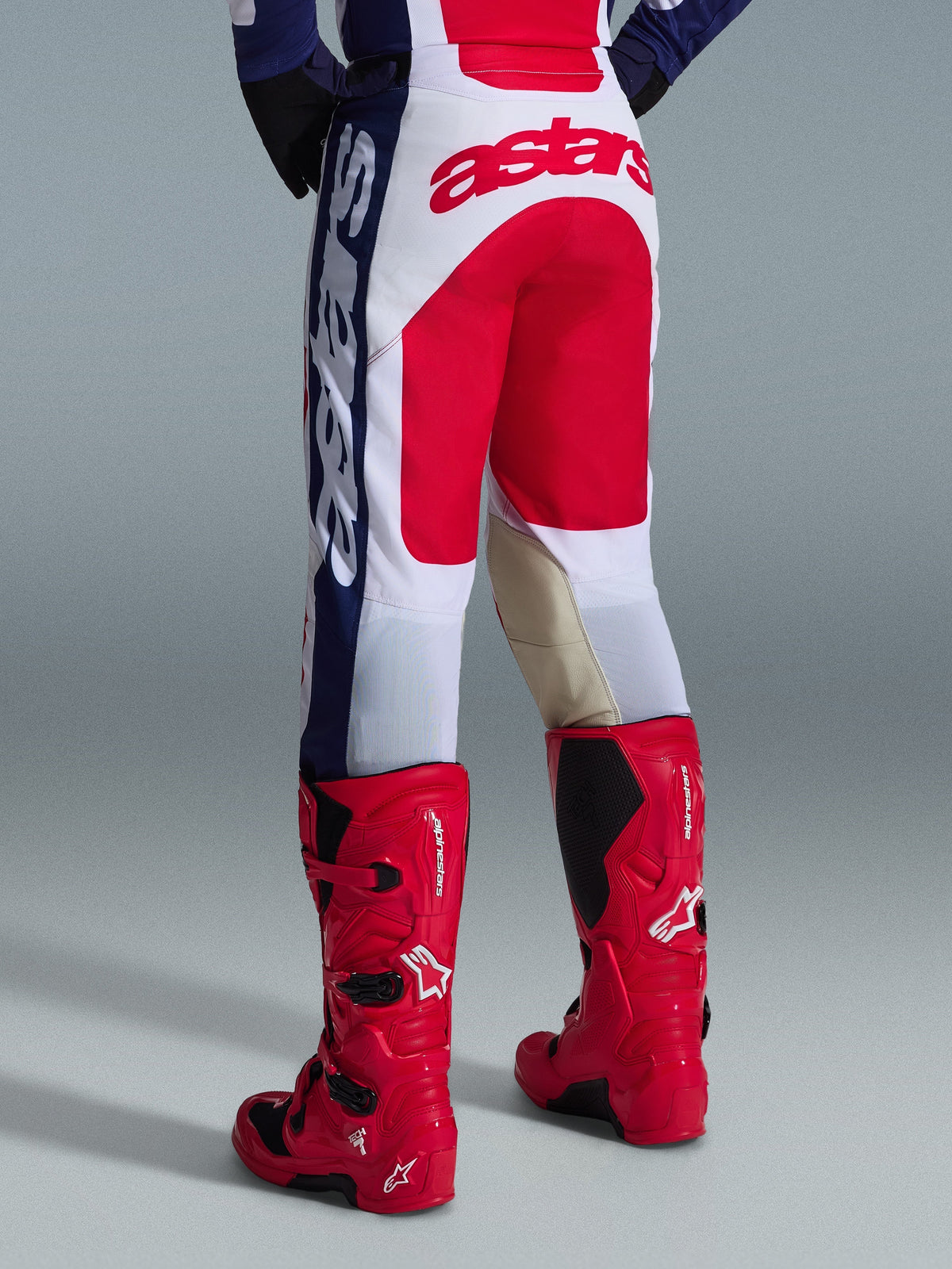Alpinestars 2026 Racer Riway Pants, Motocross Pants, White Blue and Red, rear view showing large red Astars logo on seat and tan leather inner knee panels, worn with red Alpinestars motocross boots, performance gear for off-road racing
