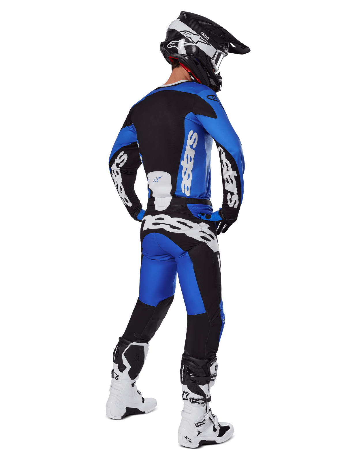 Motocross rider viewed from behind wearing Alpinestars 2025 Racer Veil Pants in Blue and Black, matching long-sleeve jersey with white branding, white and black Tech 7 boots, and a black SM10 helmet, full off-road racing gear set
