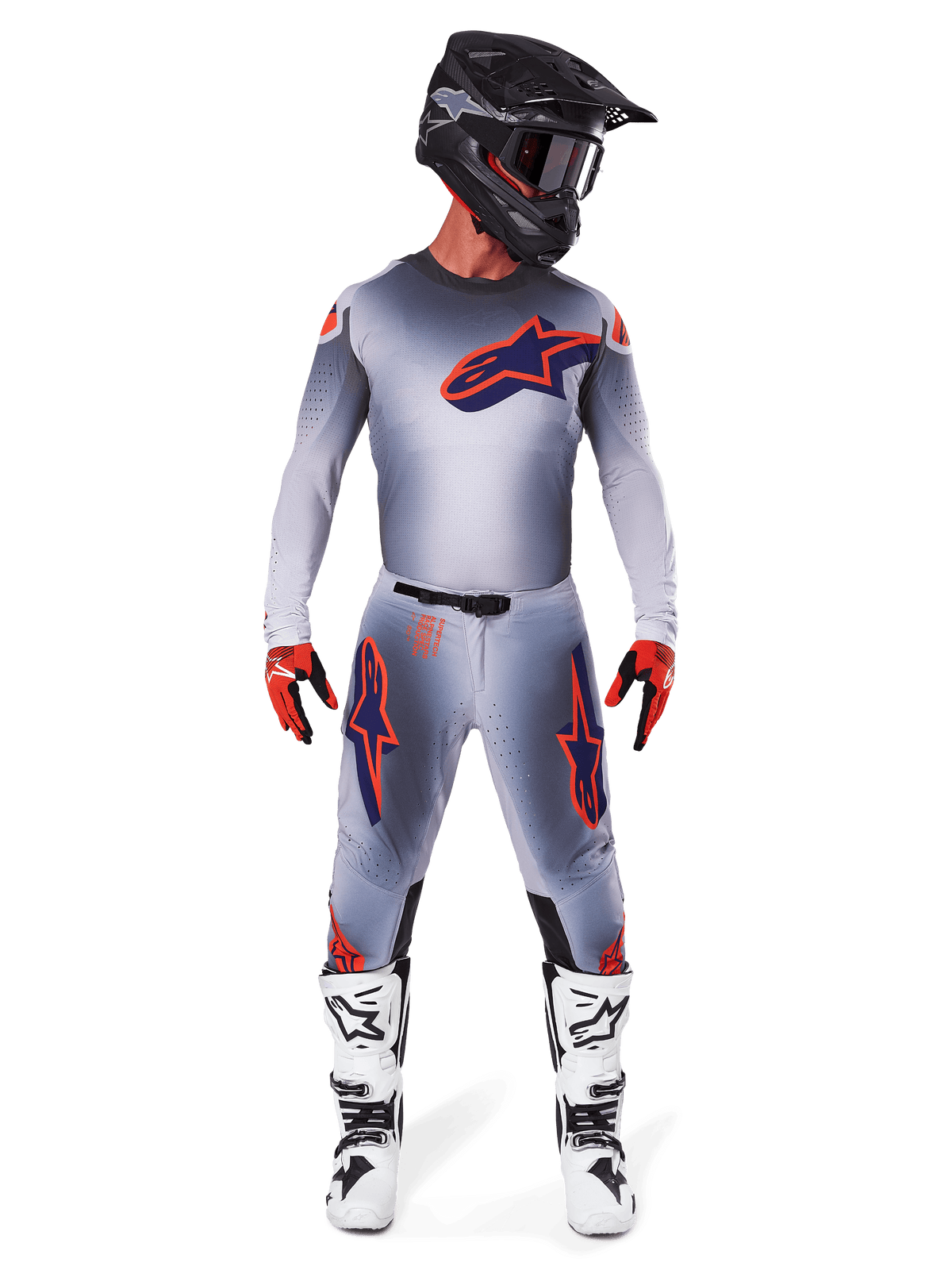 Motocross rider wearing Alpinestars 2025 Supertech Lipan Pants and matching jersey in Gray Orange Fluo, featuring bold orange and navy logos, paired with a black helmet, red gloves, and white and black boots, full racing kit for off-road performance.