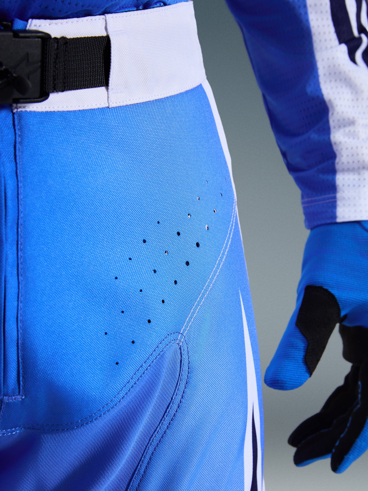 Alpinestars 2026 Techstar Knif Pants, Motocross Pants, Ucla Blue and Black, close-up view of thigh with laser-cut perforations and SX2 magnetic waist buckle, technical construction for off-road racing