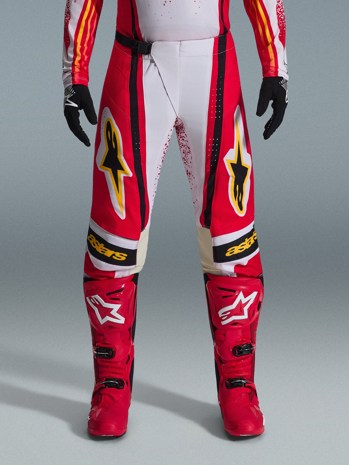 Alpinestars 2026 Techstar Nomur Pants, Motocross Pants, Red and White with black and yellow accents, worn with matching red boots and black gloves, performance off-road racing gear