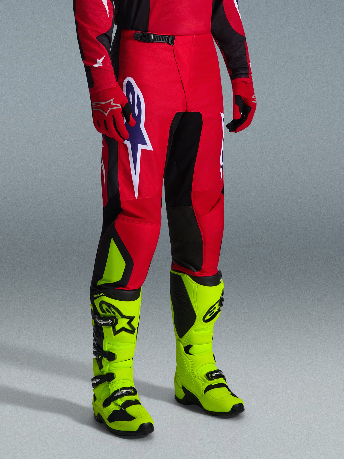 Alpinestars 2026 Fluid Grid Pants, Motocross Pants, Red Black and Purple, worn with neon yellow boots and red gloves, featuring black panels and a large purple and white star logo, durable sport-fit design for off-road racing