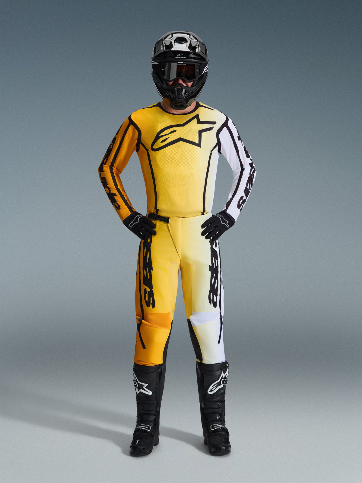 Alpinestars 2026 Fluid Apex Pants, Motocross Pants in Yellow Black and White, worn as a complete racing kit with matching gradient jersey, black helmet, and boots, professional off-road riding gear.