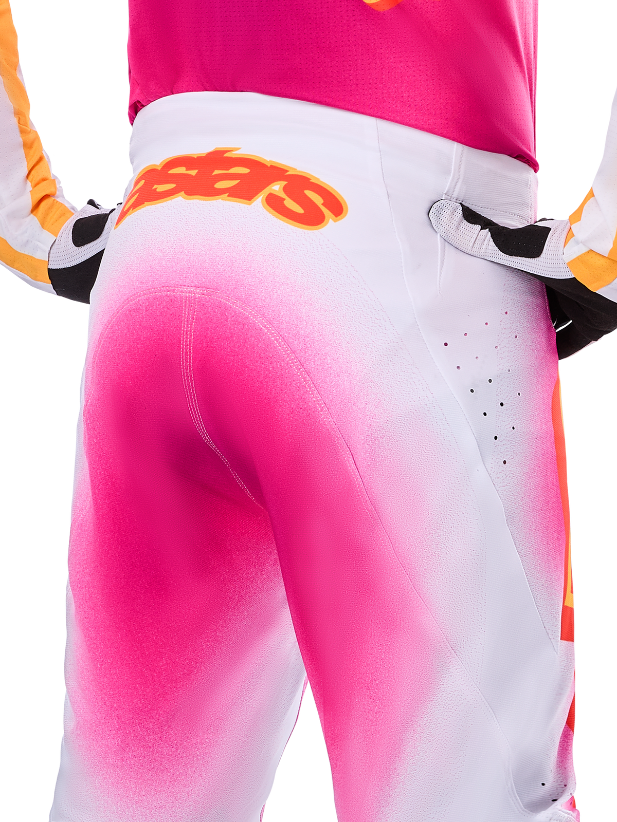 Alpinestars Limited Edition Supertech AFD MIG Pants, Motocross Pants, Pink Fluo and White with a spray-paint fade effect, large orange Alpinestars logo on the rear waistband, close-up view showing athletic fit and ventilation perforations.