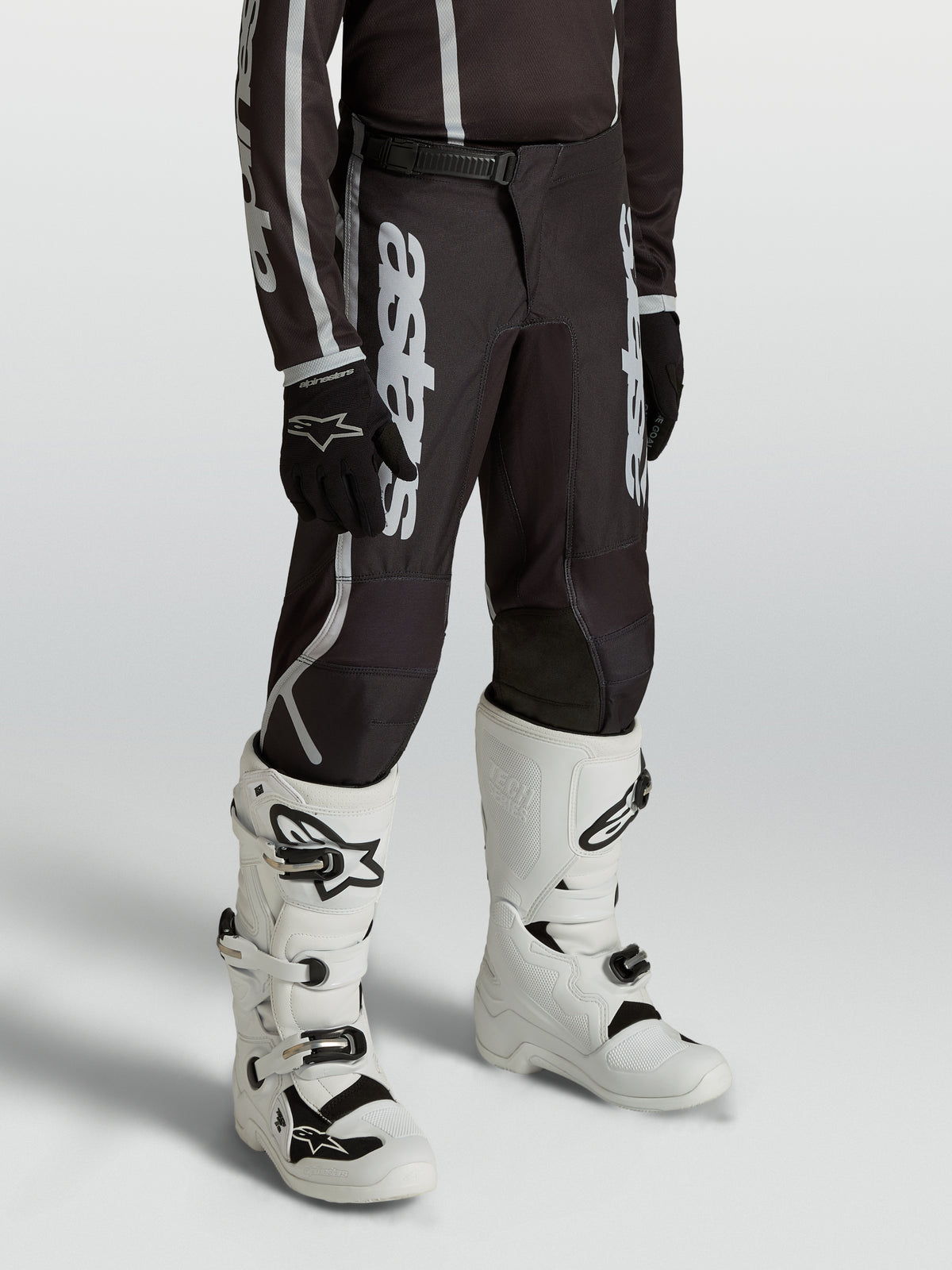 Alpinestars Youth Fluid Apex V2 Pants, black and silver motocross gear for young riders, featuring an ergonomic pre-curved fit.