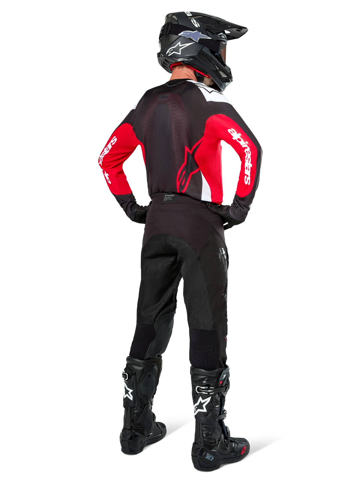 Motocross rider from behind wearing the Alpinestars Pro-Dura Jersey in Black, Bright Red, and White, paired with black motocross pants, helmet, and boots, showing the rear design and sleeve logos, coordinated off-road racing gear.