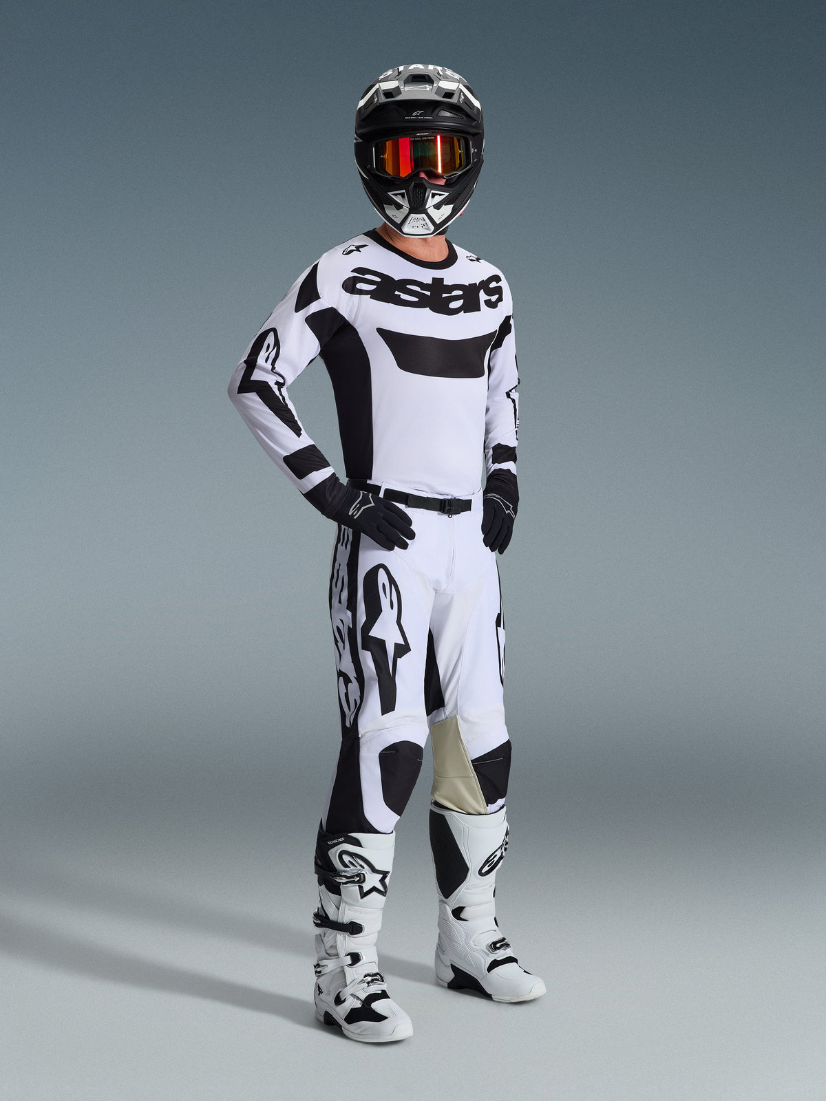 Alpinestars 2026 Racer Riway Gear Set, Motocross rider in a white and black racing kit, white jersey with black 'astars' chest logo, white pants with black accents, black helmet with orange goggles, white boots, coordinated gear for motocross and off-road riding