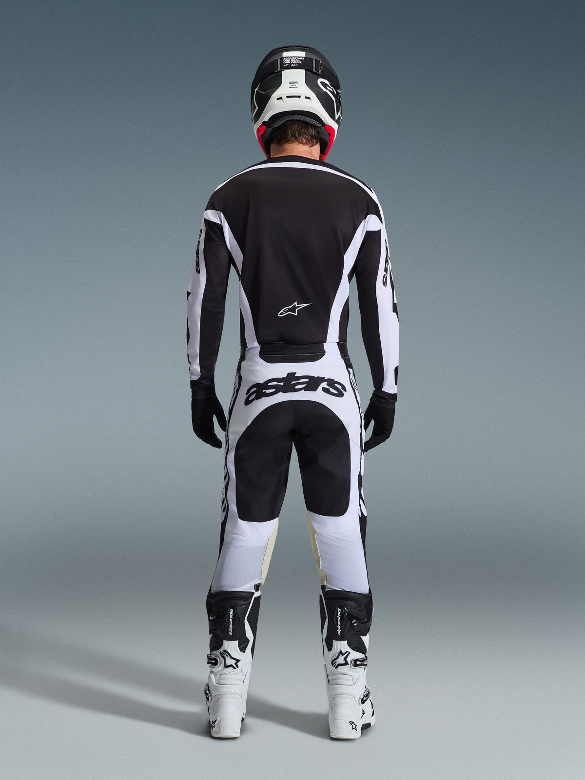 Rear view of a motocross rider wearing the 2026 Racer Riway Gear Set in Black and White, featuring a black jersey with white accents, white pants with bold 'astars' branding on the seat, black helmet, white boots, and black gloves, complete professional off-road racing outfit.