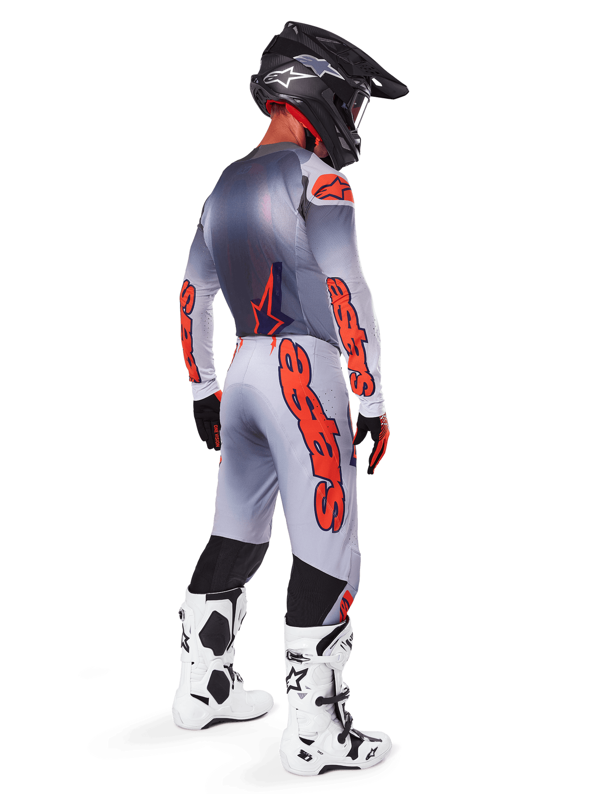 Motocross rider from behind wearing the 2025 Supertech Lipan Gear Set, Gray and Orange Fluo jersey with matching pants, bold orange Alpinestars branding on sleeves and legs, black helmet, white and black motocross boots, coordinated professional off-road racing outfit.