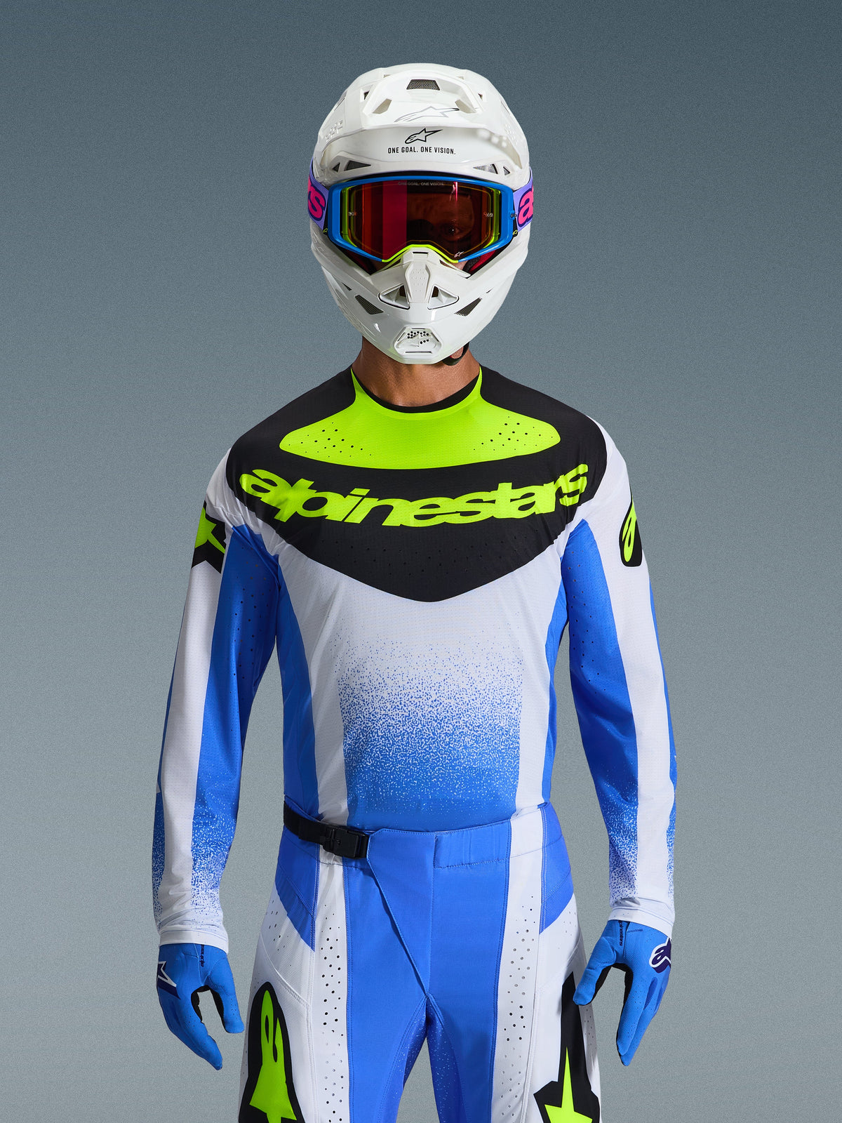 Alpinestars 2026 Techstar Knif Gear Set, Motocross rider wearing blue, white, and neon yellow racing gear, jersey with a black chest panel and neon yellow branding, white helmet with multi-colored goggles, matching blue gloves and pants, high-performance athletic racing outfit for off-road competition