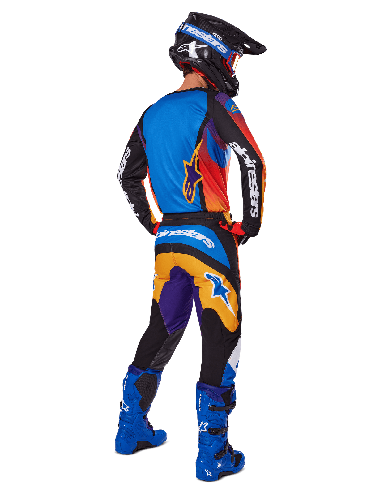 Motocross rider viewed from the back wearing Alpinestars 2025 Fluid Wurx Gear Set, multicolor jersey with blue orange and purple panels, matching pants with white Alpinestars logo on the seat, bright blue boots and a black helmet, coordinated outfit for off-road racing