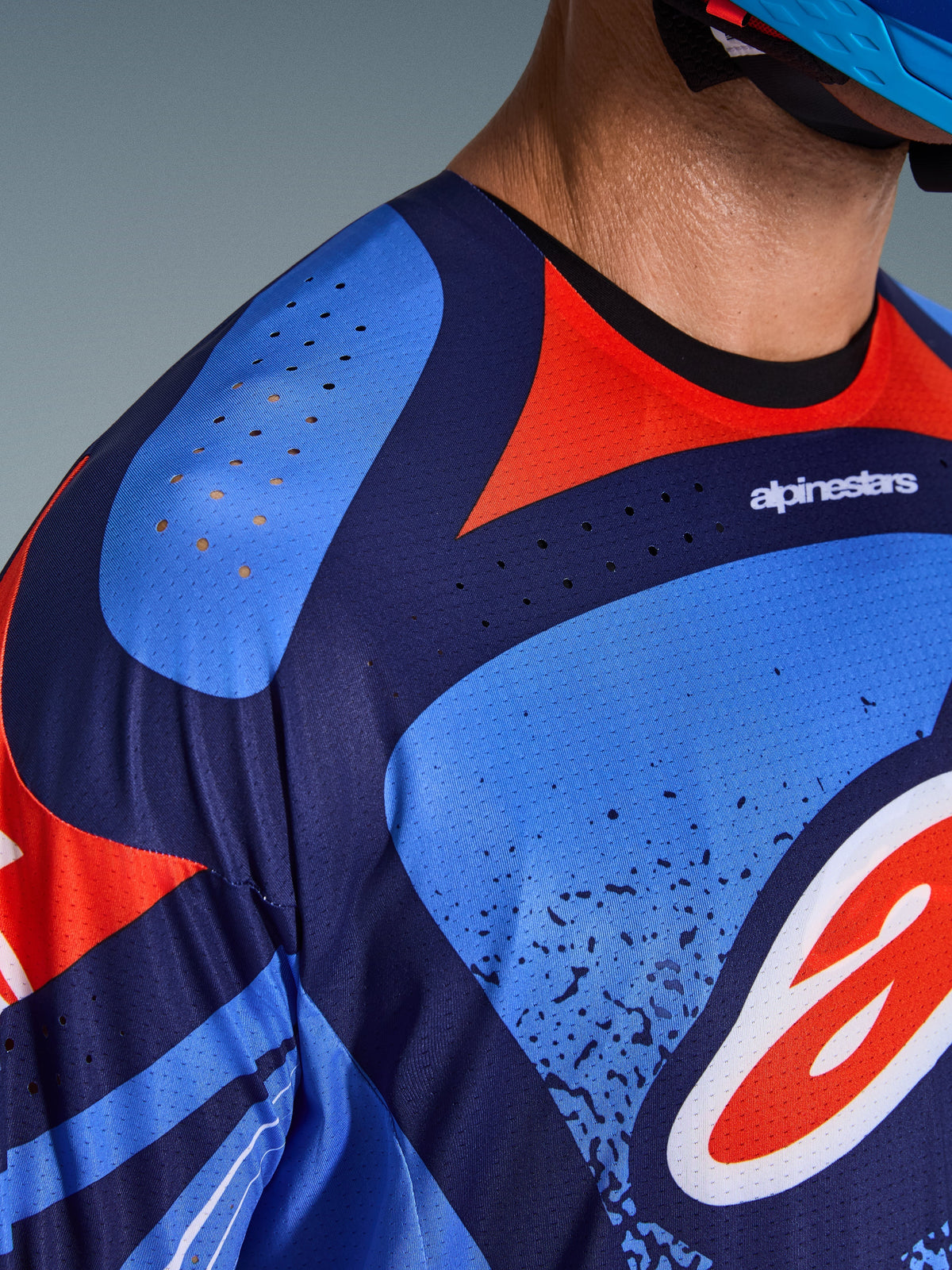Close-up of Alpinestars 2026 Techstar Nomur Jersey, Motocross Jersey, Dark Navy Orange and UCLA Blue, featuring laser-cut ventilation holes on the shoulder and chest, technical moisture-wicking fabric, athletic race fit design