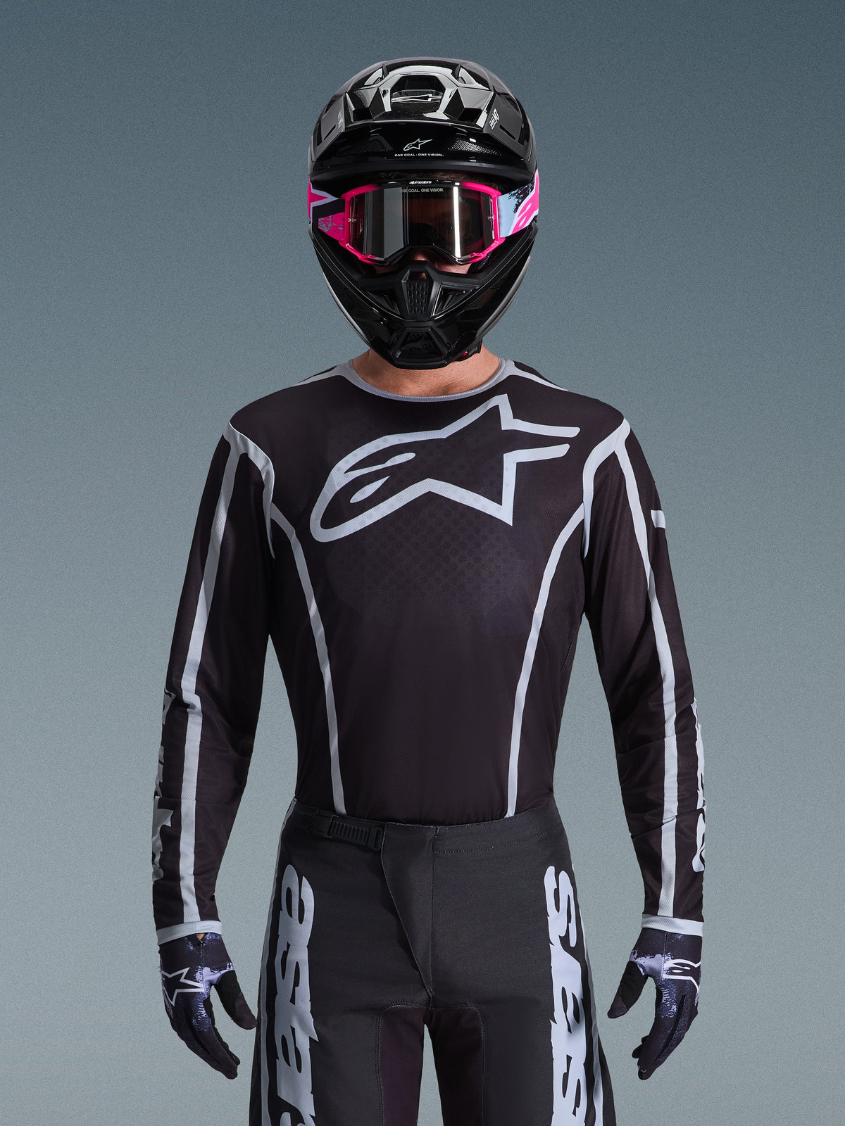 Alpinestars 2026 Fluid Apex Gear Set, Motocross jersey and pants in black and white, features large chest logo and geometric line designs, worn with a black helmet and pink goggles, performance gear for off-road motocross racing.