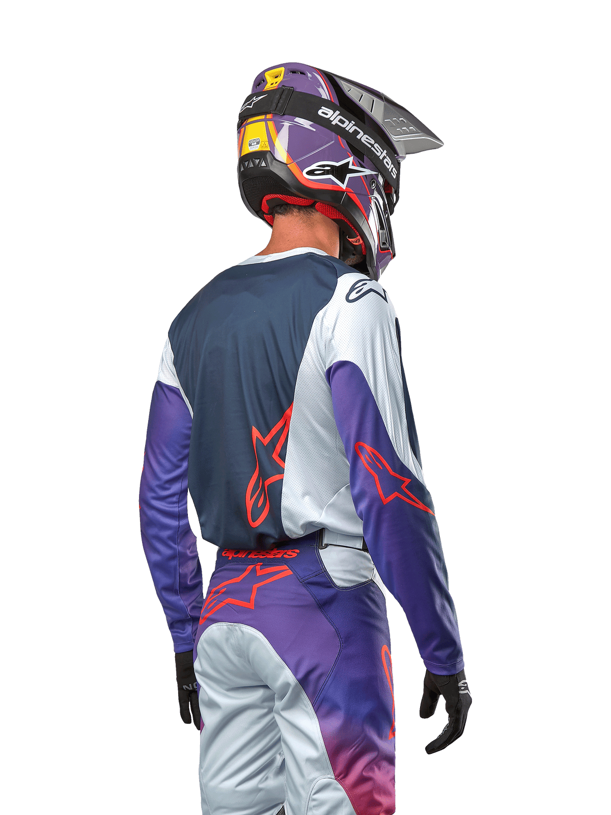 Motocross rider viewed from the back wearing the 2024 Racer Hoen Jersey, navy blue back panel with light gray shoulders and purple sleeves, hot orange Alpinestars logos, matching purple and gray pants with a purple motocross helmet, complete off-road racing kit