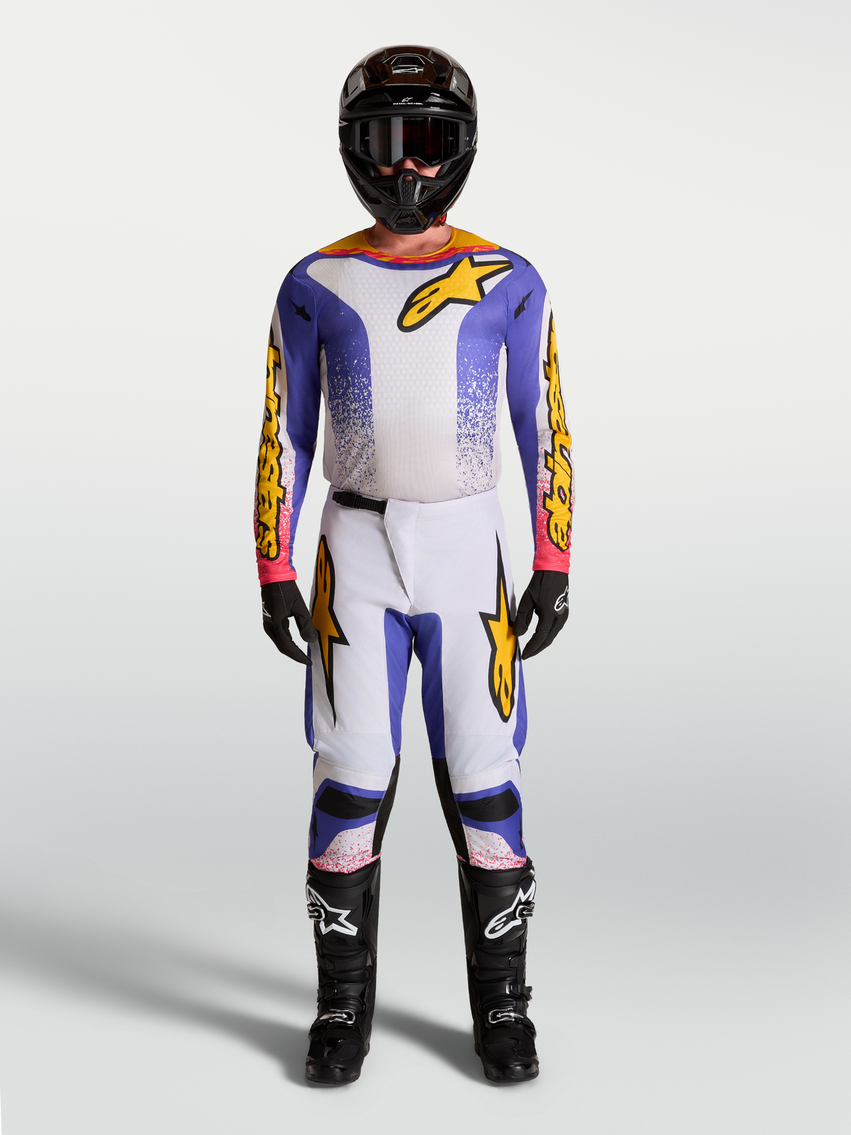 Alpinestars Fluid Drag motocross gear set in lilac, blue, and gold, featuring a matching jersey and pants.