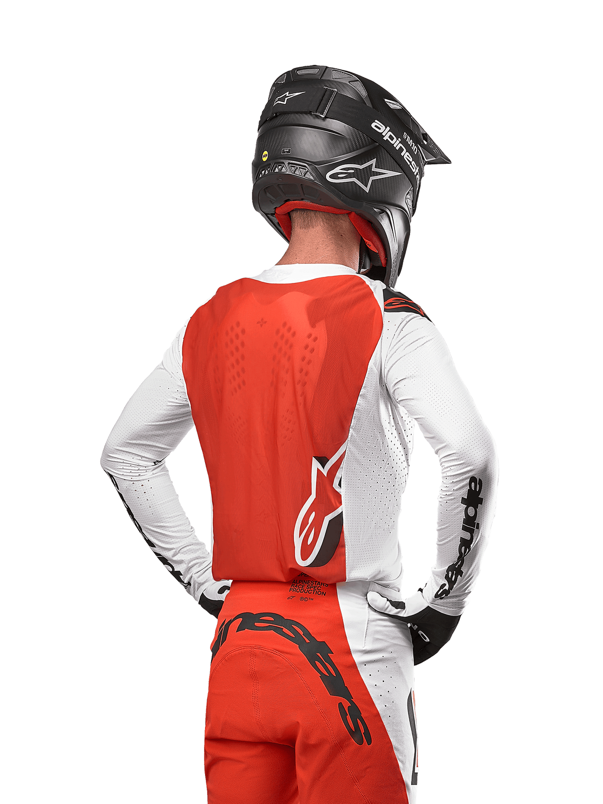Motocross rider wearing the 2024 Supertech Ward Jersey in White Hot Orange, rear view showing orange back panel and white sleeves with black Alpinestars branding, paired with matching pants and a black helmet, coordinated professional gear for off-road racing