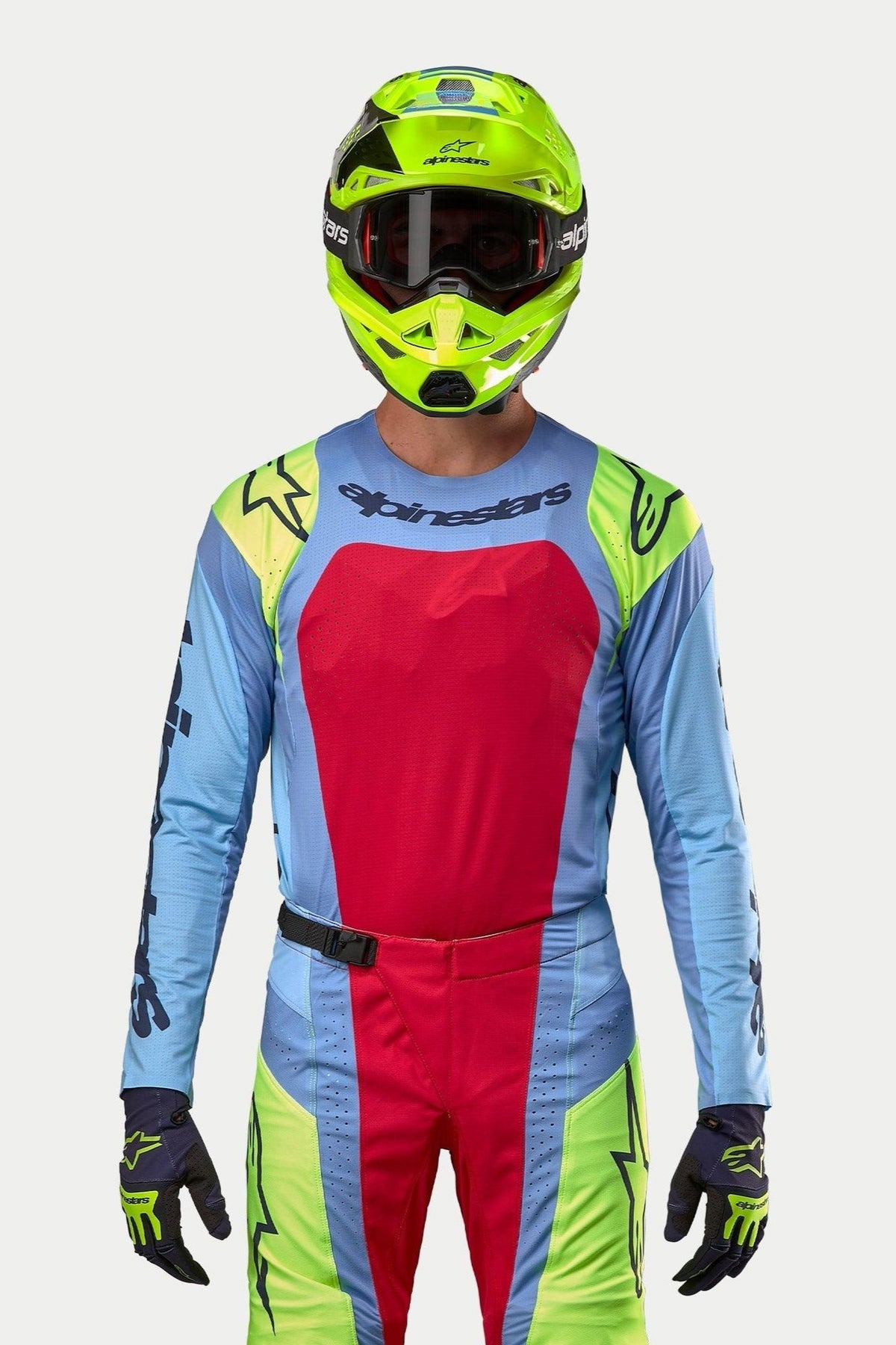 Motocross rider wearing complete racing gear, 2024 Techstar Ocuri Jersey in Light Blue with a large Red Berry chest panel and Yellow Fluo shoulder accents, matching fluorescent yellow helmet, coordinated red and yellow fluo pants, professional outfit for off-road racing