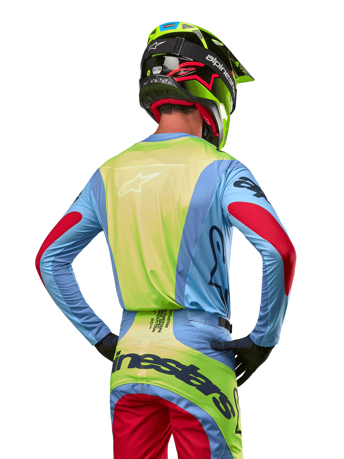 Motocross rider from behind wearing the Alpinestars 2024 Techstar Ocuri Jersey, Light Blue with Fluo Yellow back and Red sleeve accents, matching motocross pants and neon yellow helmet, coordinated outfit for off-road racing