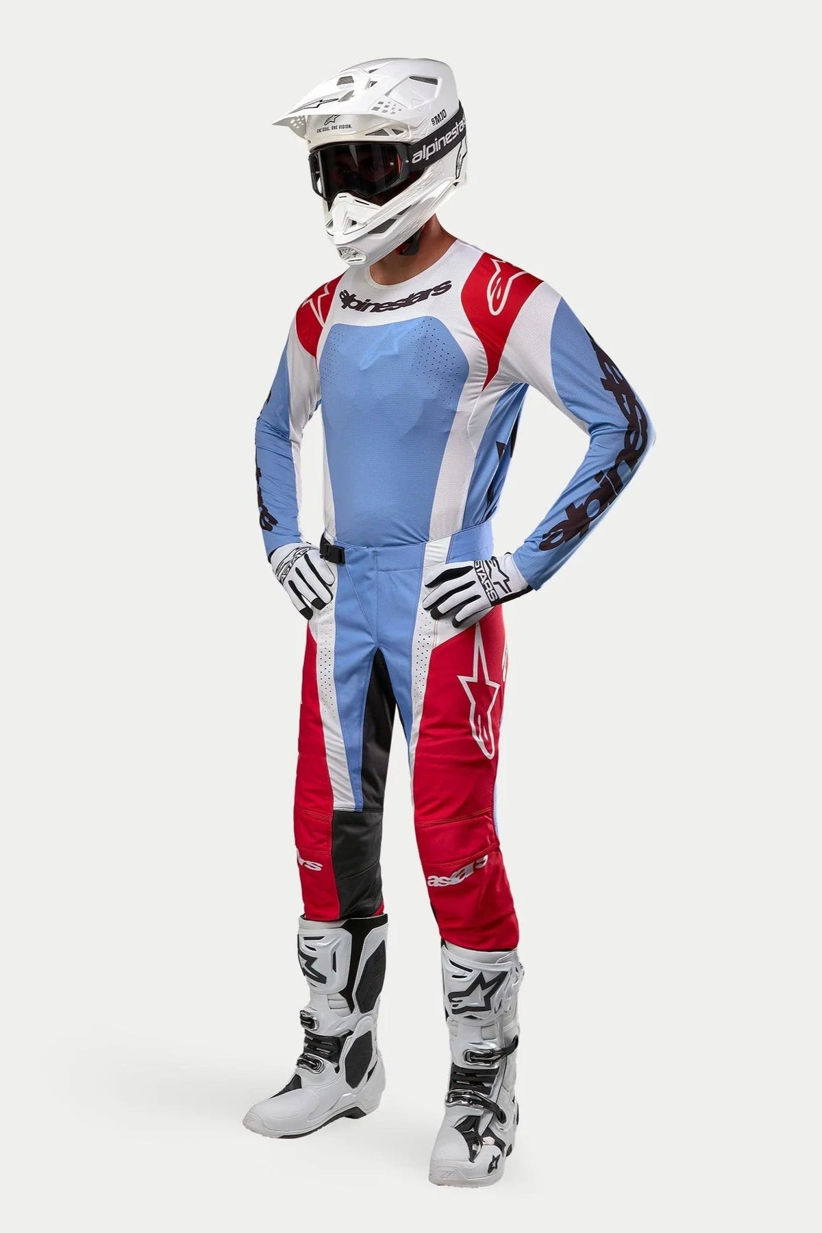Motocross rider wearing complete racing gear featuring the Alpinestars 2024 Techstar Ocuri Jersey in Light Blue, Mars Red, and White, paired with matching pants, white helmet with goggles, white boots, and white and black gloves.