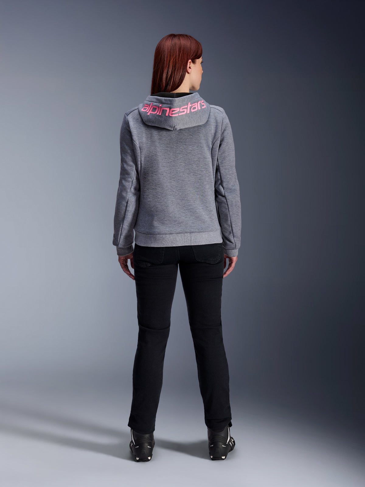 Alpinestars Stella Chrome V2 Sport Hoodie, Women's Motorcycle Hoodie, Gray Heather and Pink Fluo, back view showing pink Alpinestars logo on the hood, worn with black riding pants and boots, casual motorcycle apparel for women