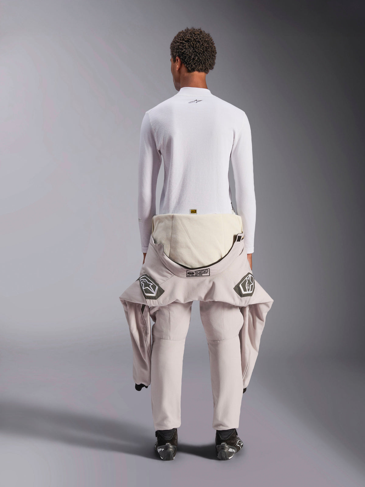 Alpinestars ZX Evo V3 Top - Long Sleeve, White auto racing base layer, back view of a person wearing the flame-resistant top with a racing suit pulled down to the waist, paired with black racing boots, professional motorsport underwear