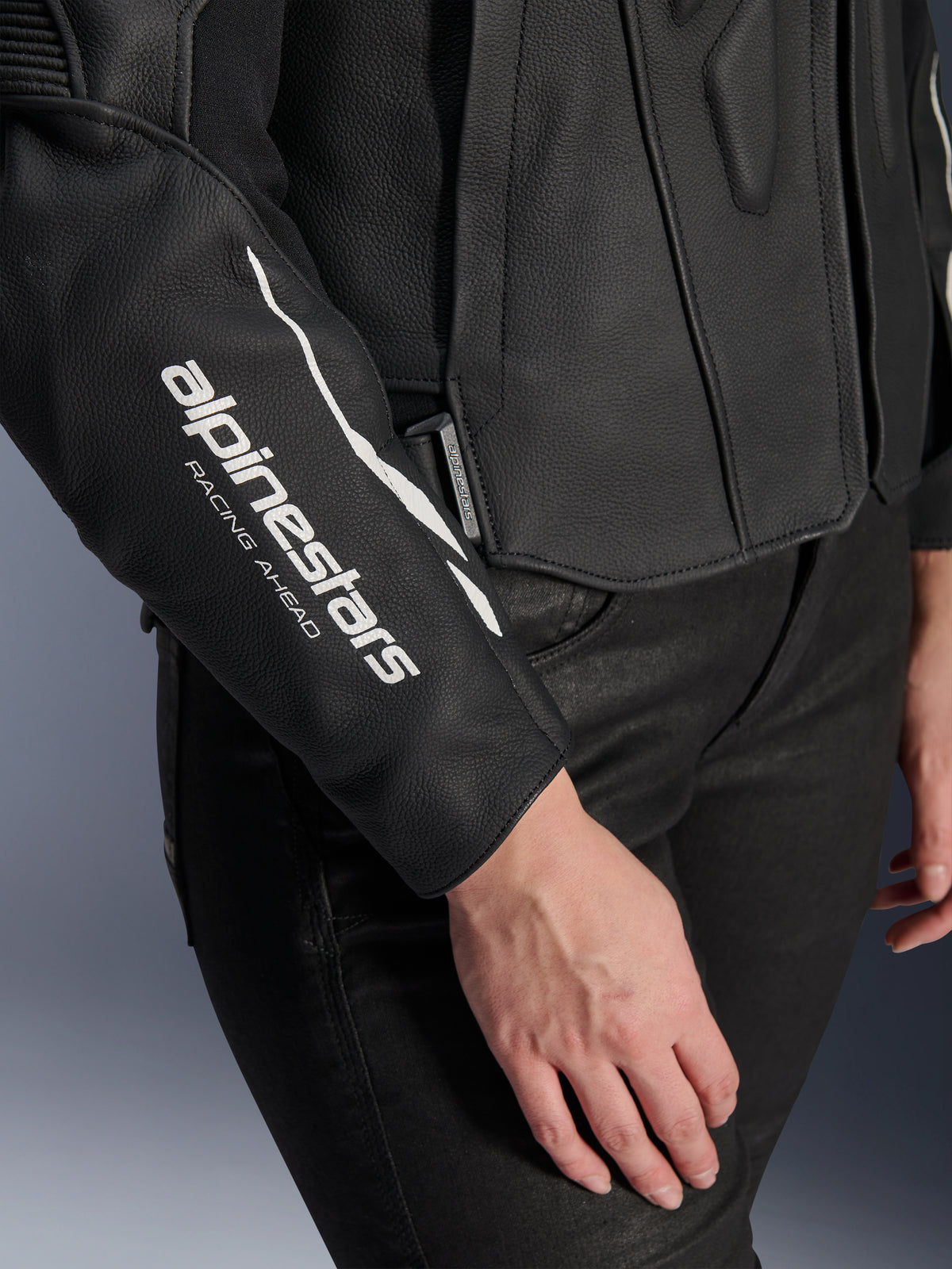 Close-up of Alpinestars Stella Dusk Leather Jacket, Women's Black Leather Motorcycle Jacket, featuring white 'alpinestars RACING AHEAD' logo on the sleeve, premium bovine leather texture, worn with black pants