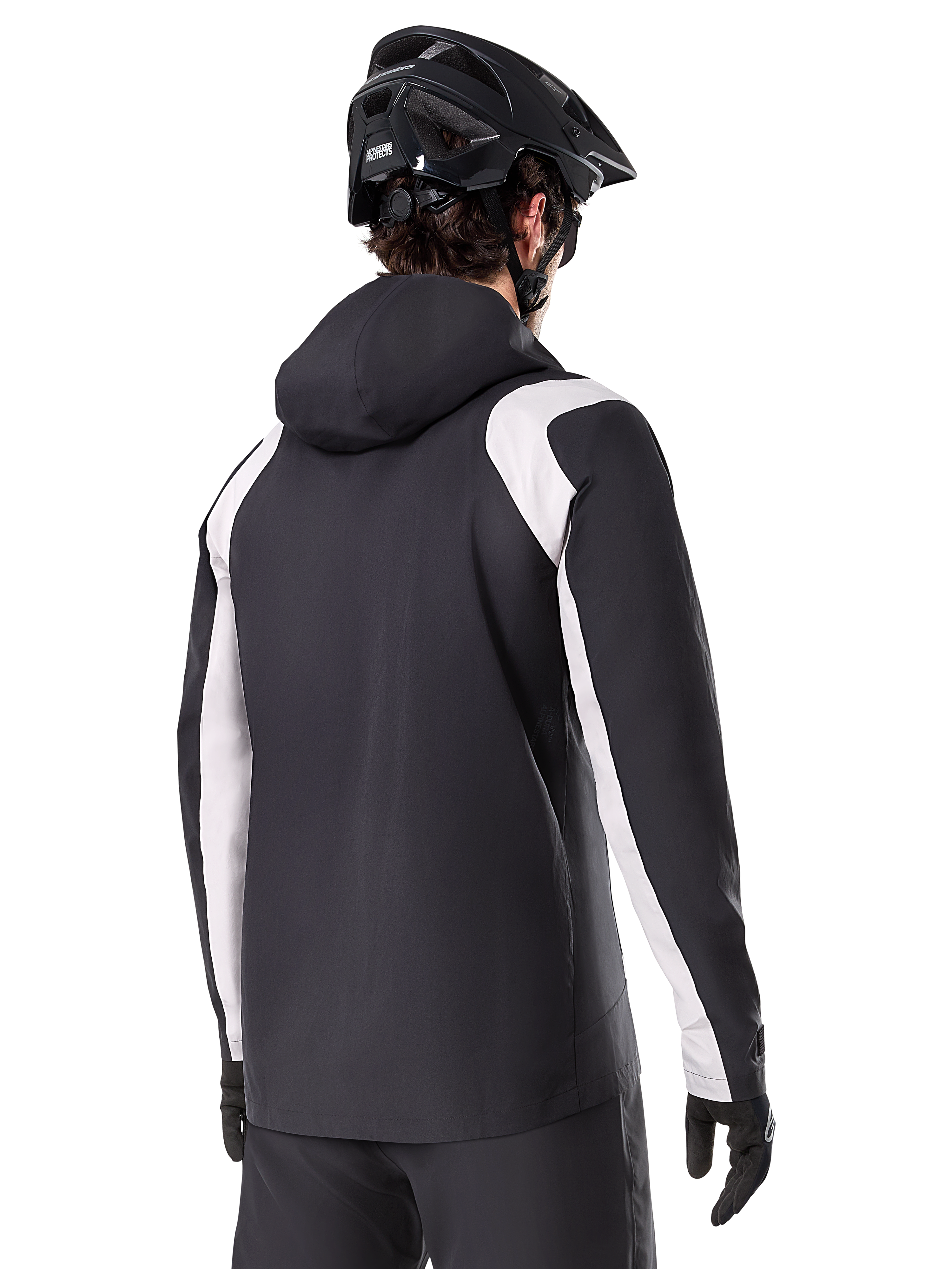 Alpinestars A-Dura Rain Jacket, Mountain Bike Rain Jacket, Black with white sleeve panels, rear view of rider wearing a black MTB helmet and gloves, technical 2.5-layer waterproof construction, mountain biking apparel