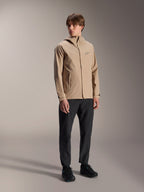 Male model wearing the Alpinestars A-Dura Rain Jacket in Light Brown, paired with black pants and shoes, minimalist outdoor mountain bike rain jacket featuring a hooded design and a small chest logo.