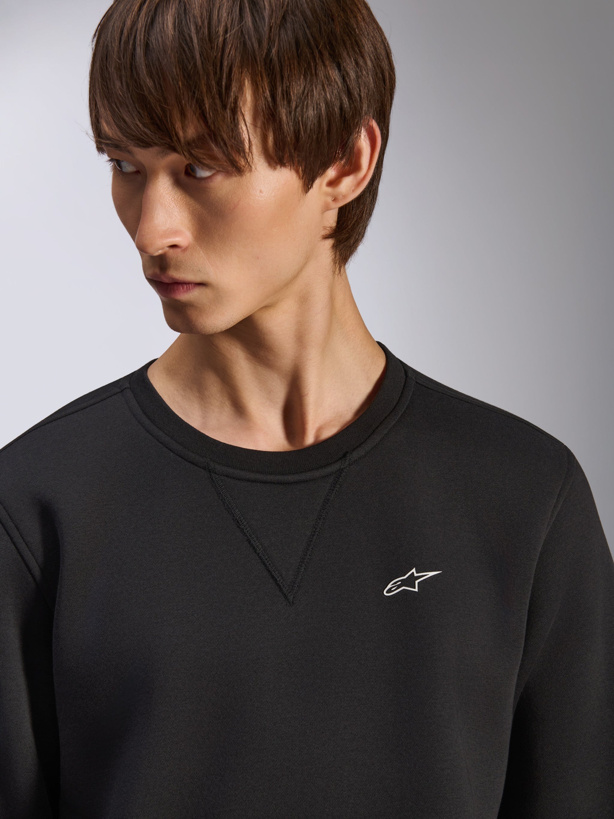 Alpinestars Positive Crew sweatshirt, black crewneck with V-stitch detail at the neck, small white Alpinestars logo on the left chest, casual motorsport-inspired streetwear