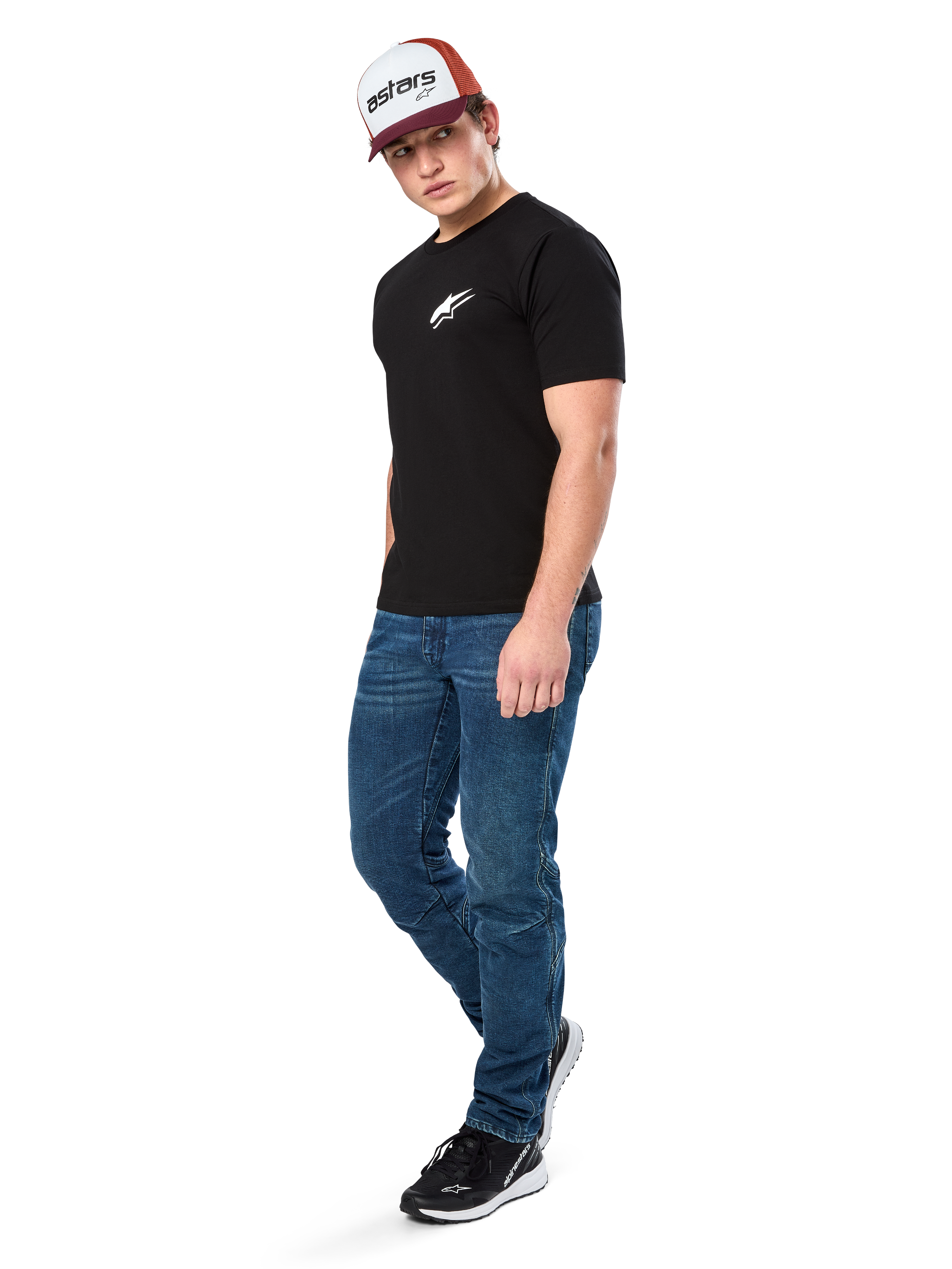 Alpinestars Formulate Csf Tee, Short Sleeve T-Shirt, Black with white Astars chest logo, worn by a model with blue jeans, a burgundy and white cap, and black sneakers, casual motorsport-inspired streetwear