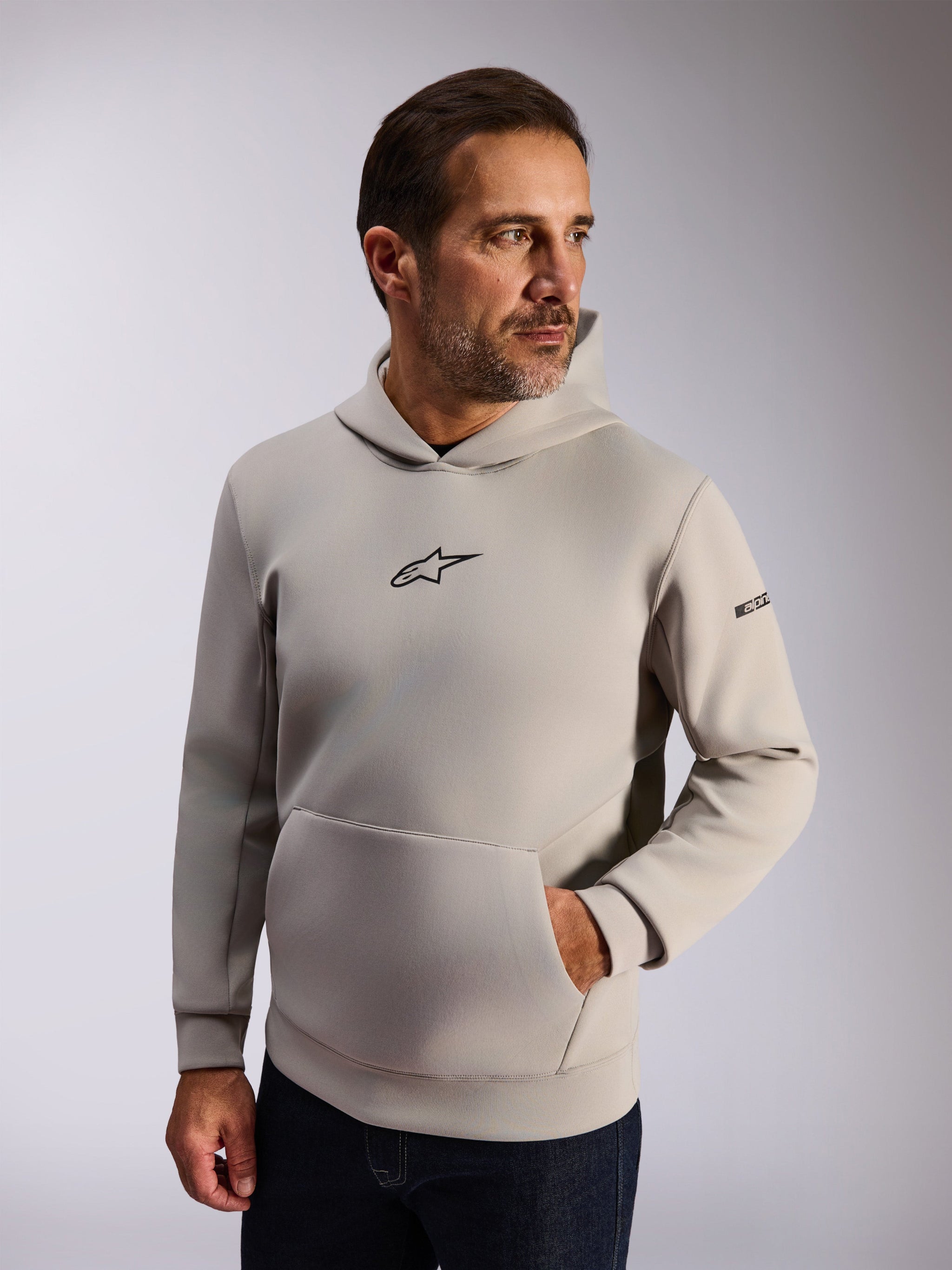 Alpinestars Insight Hoodie, casual lifestyle streetwear, Cement gray fleece, front black Astars logo, kangaroo pocket, sleeve wordmark, mesh-lined hood, modern motorsport-inspired apparel