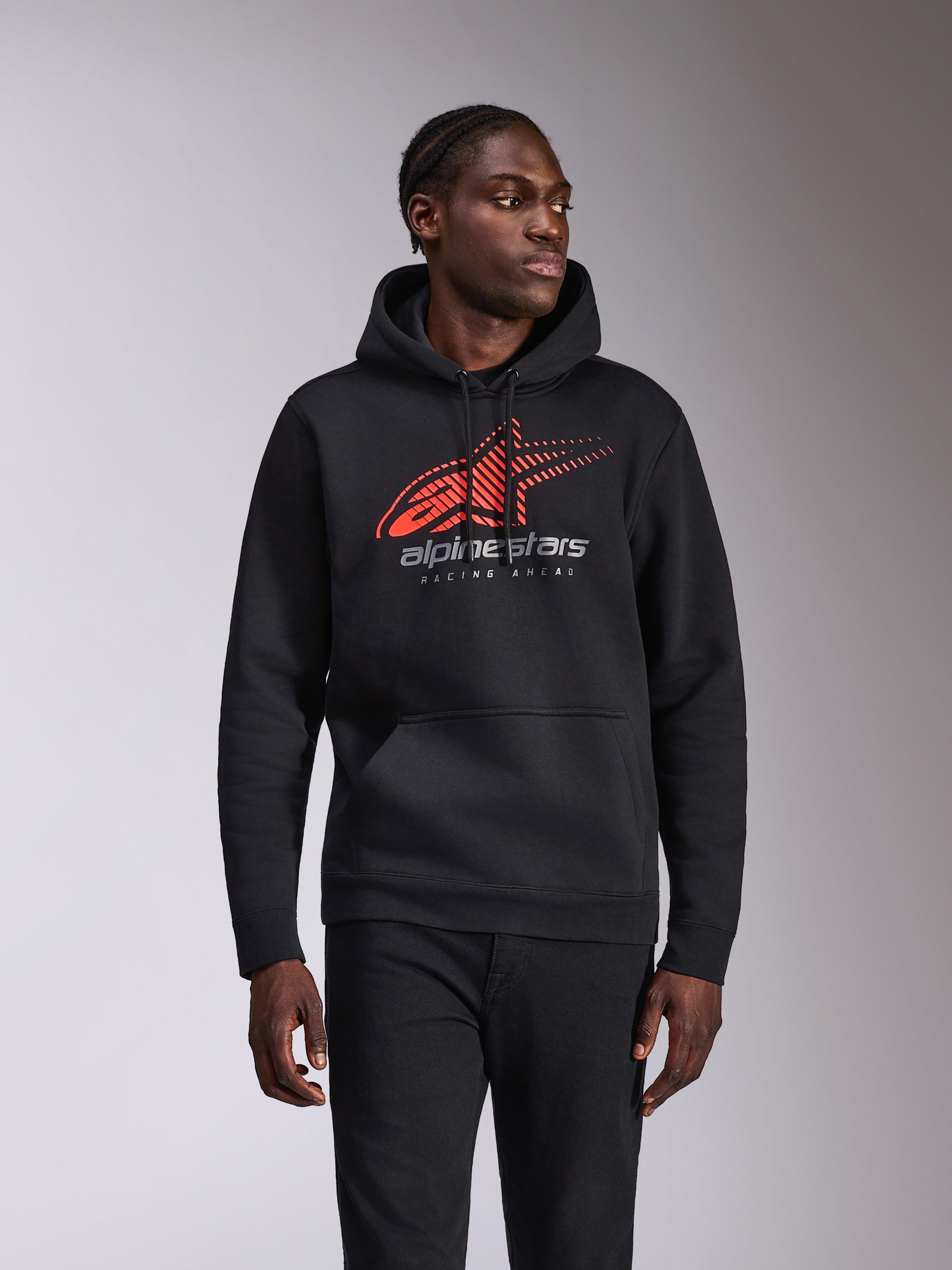 Alpinestars Pulse Hoodie, casual pullover hoodie, black with red and grey Astars logo featuring speed line fade and 'Racing Ahead' text, drawstring hood and kangaroo pocket, motorsport-inspired streetwear worn by a model