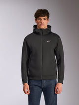 Alpinestars Cypher Hoodie, black zip-front fleece hoodie, featuring a high-neck hood with white branding and a small white Astars logo on the chest, worn by a model with blue jeans, casual motorsport-inspired streetwear.