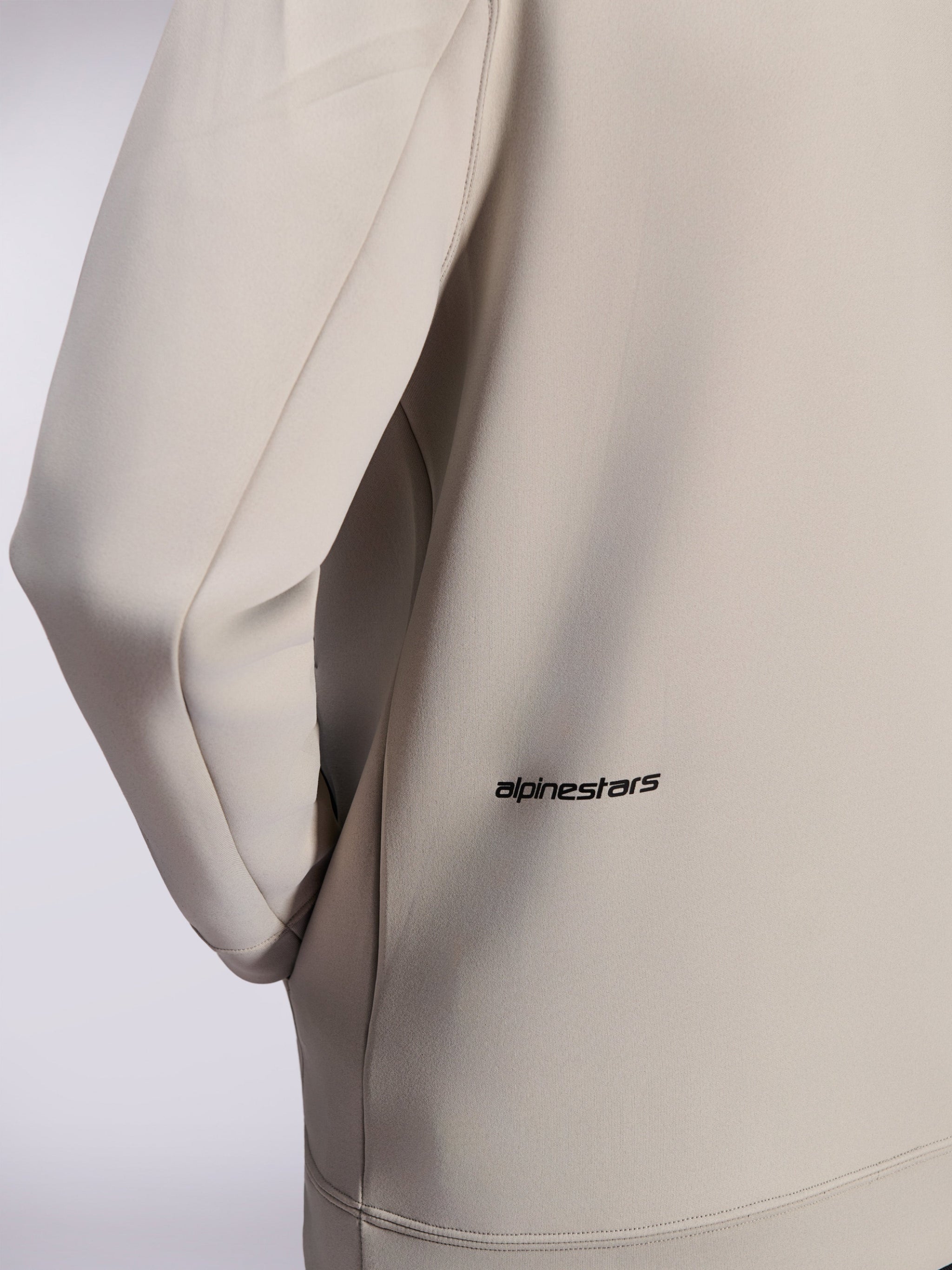 Alpinestars Cypher Hoodie, double face fleece zip hoodie, Cement Gray, close-up of small black Alpinestars word logo on the lower back, detail of on-seam pocket and smooth fabric texture
