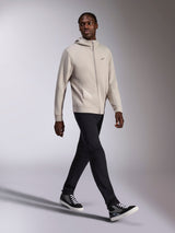 Alpinestars Cypher Hoodie, Cement gray full-zip fleece, high neck hood, small Astars chest logo, worn by a model walking, paired with black pants and black and gray sneakers, casual motorsport-inspired sportswear.