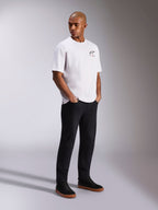 Alpinestars Wild Oversized CSF Tee, Short Sleeve T-Shirt, White, featuring a small multicolor Astars logo on the chest, worn by a model with black pants and black sneakers, casual motorsport-inspired streetwear