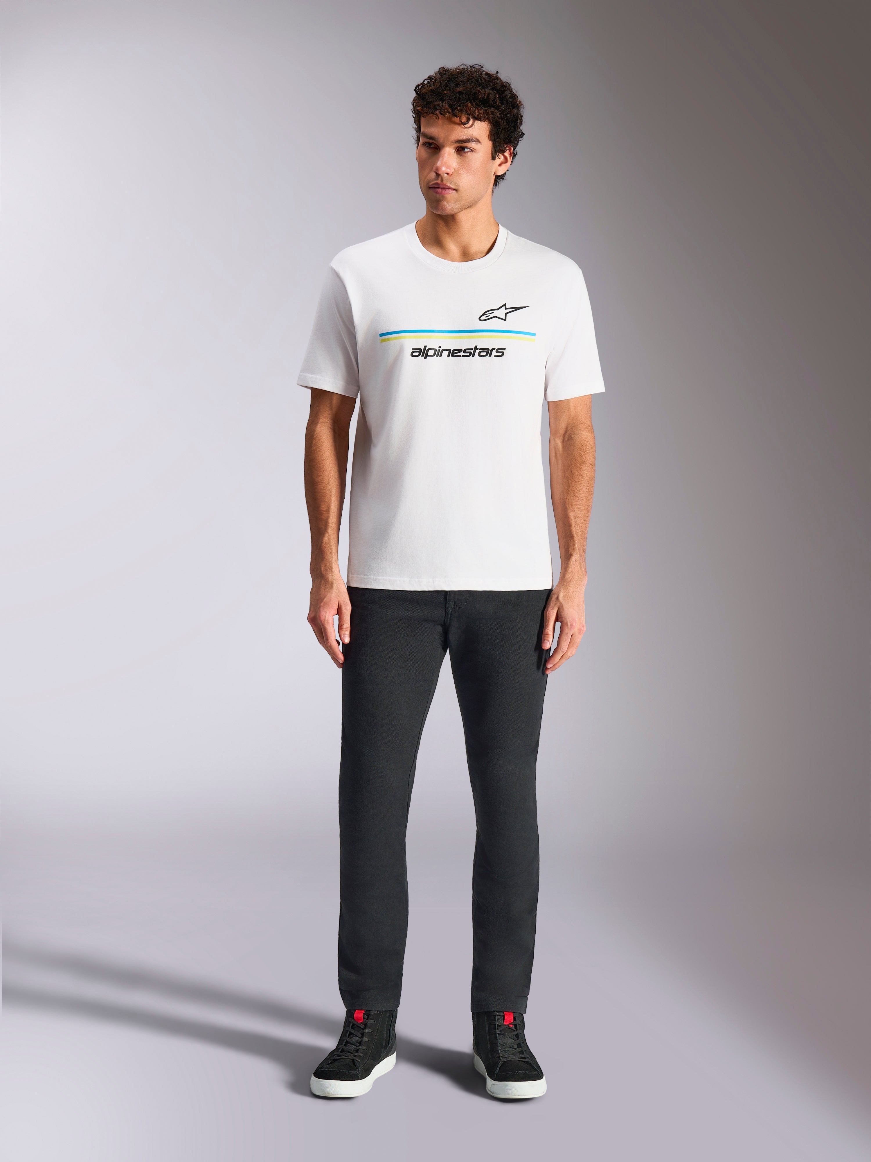 Alpinestars Lanes CSF Tee, Short Sleeve T-Shirt, White, blue and yellow stripe logo graphic, worn by model with black pants and sneakers, casual motorsport streetwear