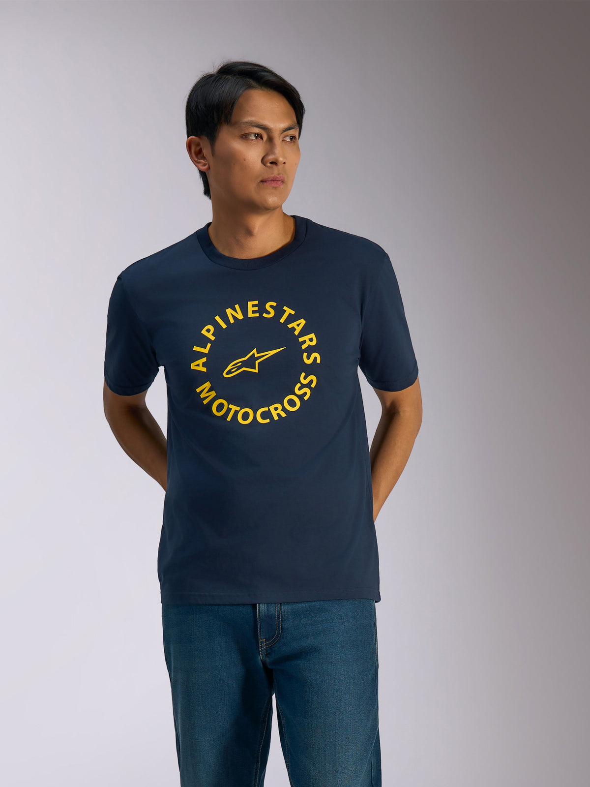 Alpinestars MX CSF Tee, Short Sleeve T-Shirt, Navy Blue, Yellow circular Alpinestars Motocross graphic with central star logo, worn by a man with blue jeans, casual motorsport streetwear