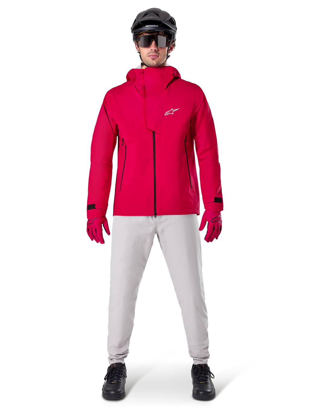 Alpinestars A-Dura Elite Waterproof Jacket, Red Fluo, technical mountain bike jacket worn with a black MTB helmet, sunglasses, matching red gloves, and light grey pants, full-body view of all-weather cycling gear