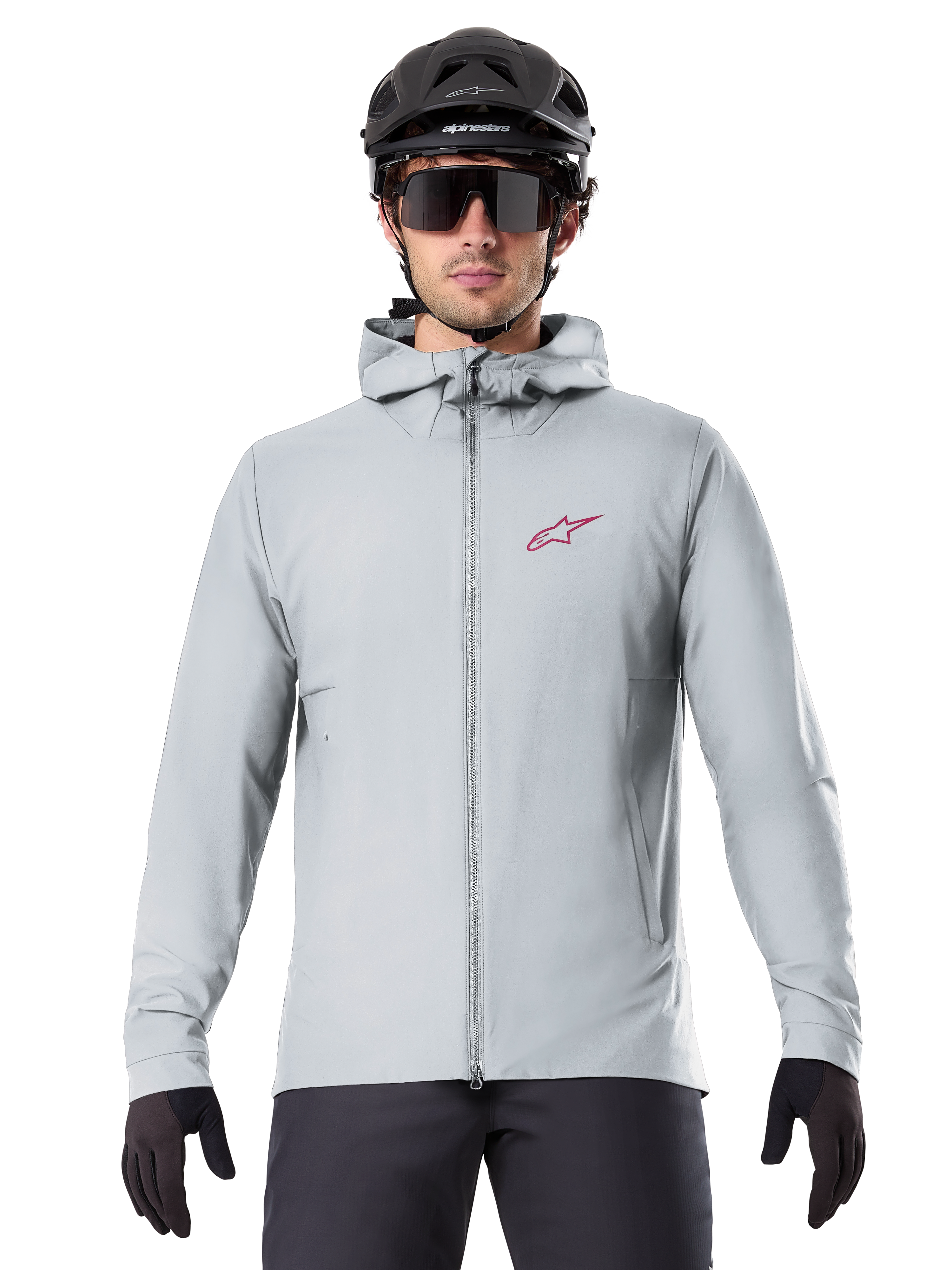 Alpinestars A-Dura Thermal Jacket in Titanium, light gray hooded cycling jacket with a red star logo on the chest, worn by a rider with a black MTB helmet, sunglasses, and gloves, insulated gear for mountain biking