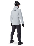 Alpinestars A-Dura Thermal Jacket in Titanium, back view of male cyclist wearing light gray hooded thermal jacket, paired with black MTB helmet, black gloves, and dark gray pants, functional mountain bike riding gear.