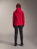 Back view of a woman wearing the Alpinestars Stella A-Dura Elite Waterproof Jacket in Red Fluo, styled with black pants and shoes, featuring a protective hood and dropped tail hem for mountain biking.