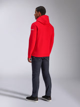 Alpinestars Frontal Hoodie, Red Pullover Fleece Hoodie, back view showing white sleeve wordmark logo, worn with dark denim pants and black shoes, casual motorsport streetwear