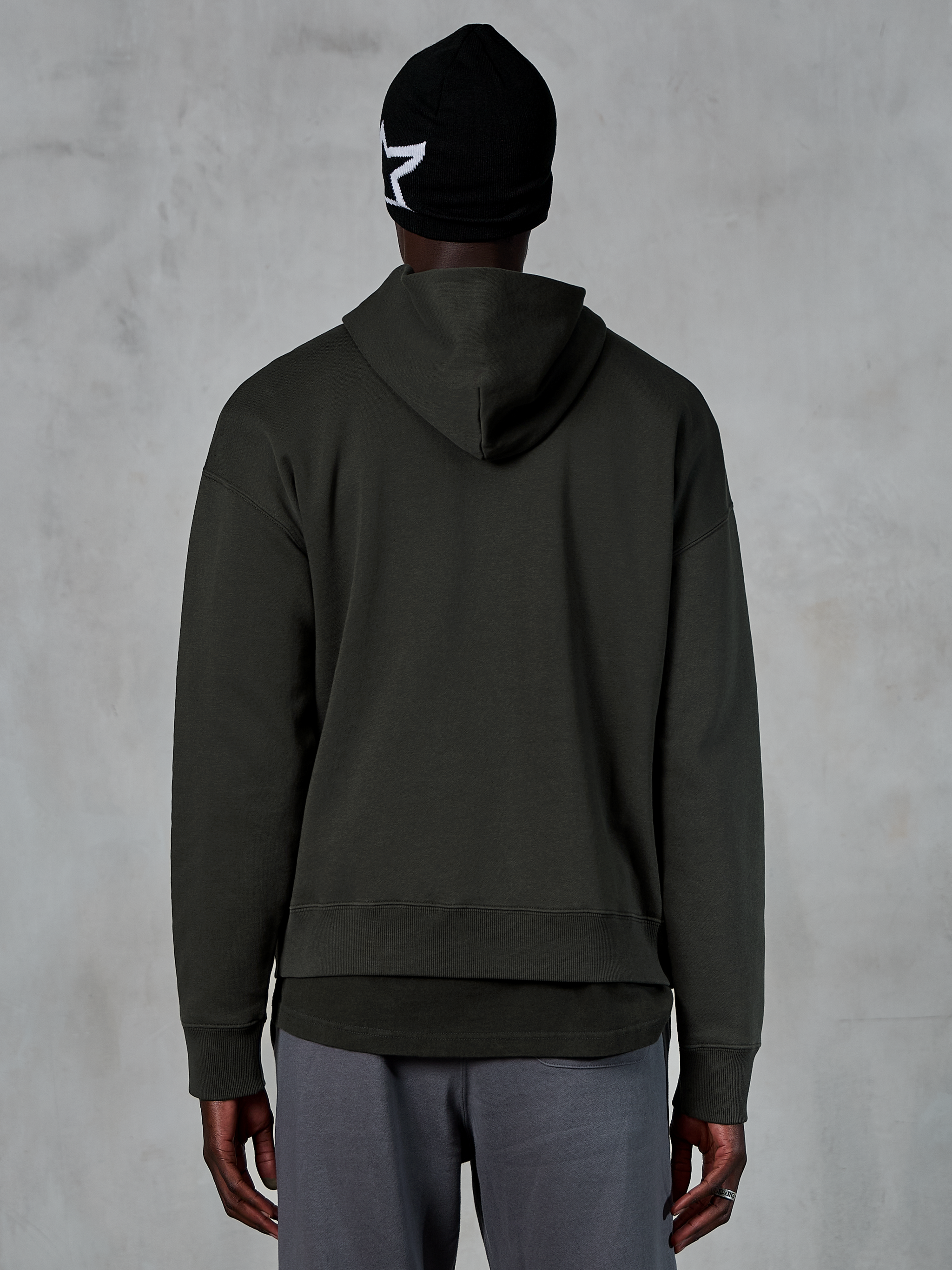 Alpinestars Essentials Ageless Hoodie, back view, Off Black, casual streetwear, model wearing black beanie with white star logo and grey pants, premium fleece with stone-wash finish